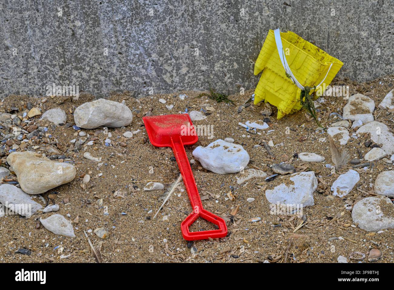 Ein Kindereimer und ein Schaufel, die auf einem britischen Strand zurückgelassen wurden Stockfoto