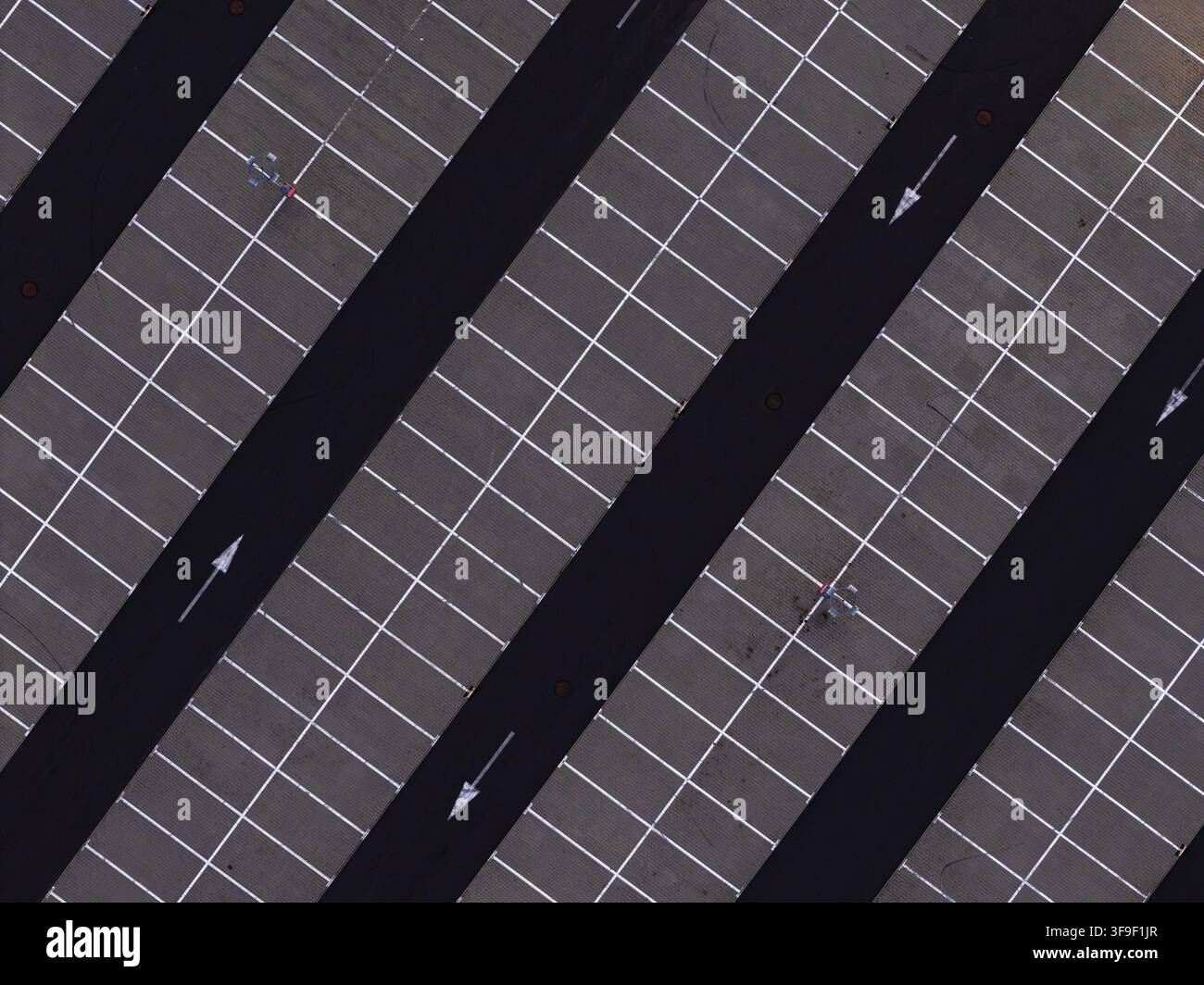 Luftaufnahme eines Parkplatzes mit diagonalen Parkplätzen, weißen Fahrbahnmarkierungen und Richtungs Pfeilen auf dem Asphalt in Polen. Stockfoto