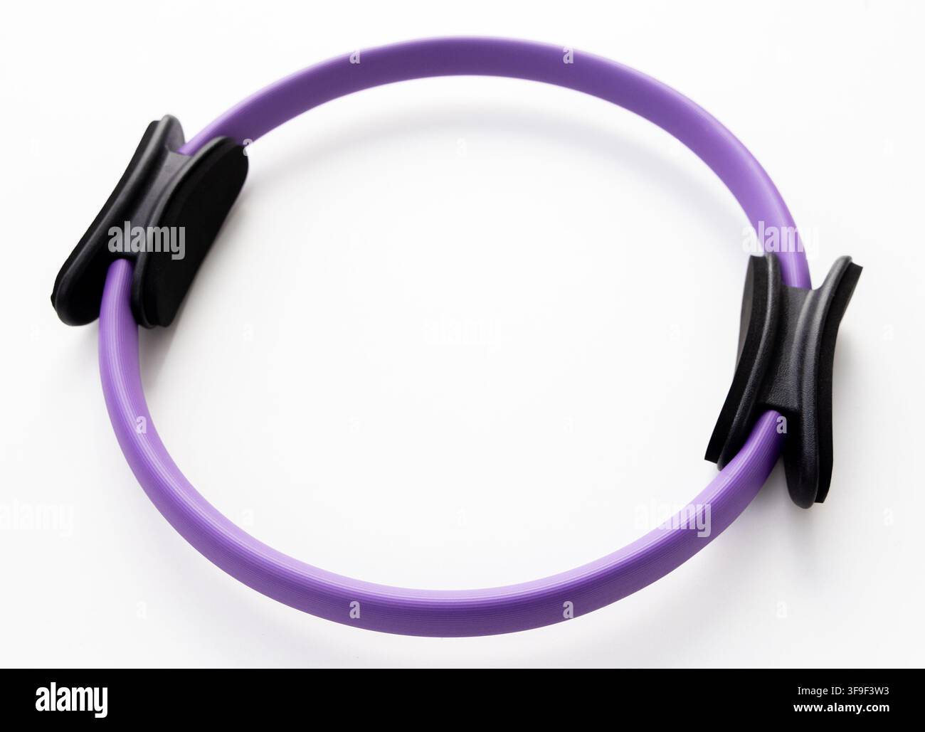 Ein violetter Pilates-Ring ruht auf einem sauberen weißen Hintergrund Stockfoto