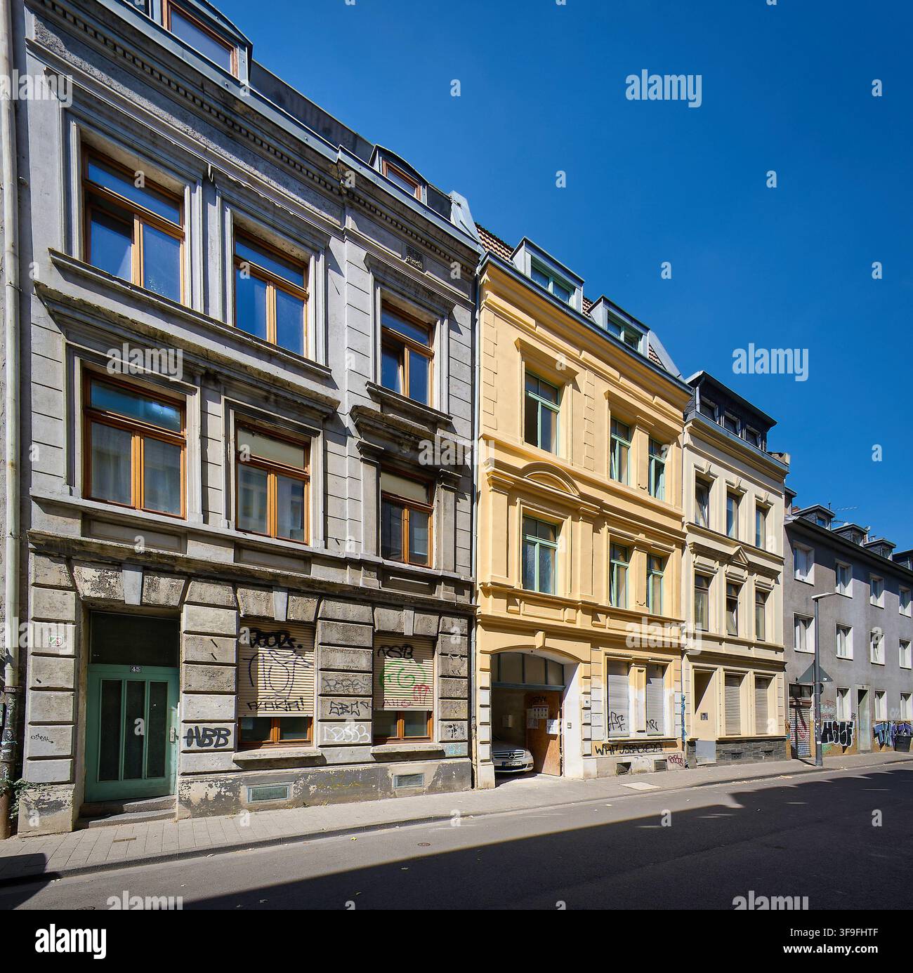 Reihe traditioneller alter Wohnhäuser mit farbenfrohen Fassaden, Fensterläden und Straßenkunst im beliebten Ehrenfeld-Viertel von Köln, Deutschland. Stockfoto