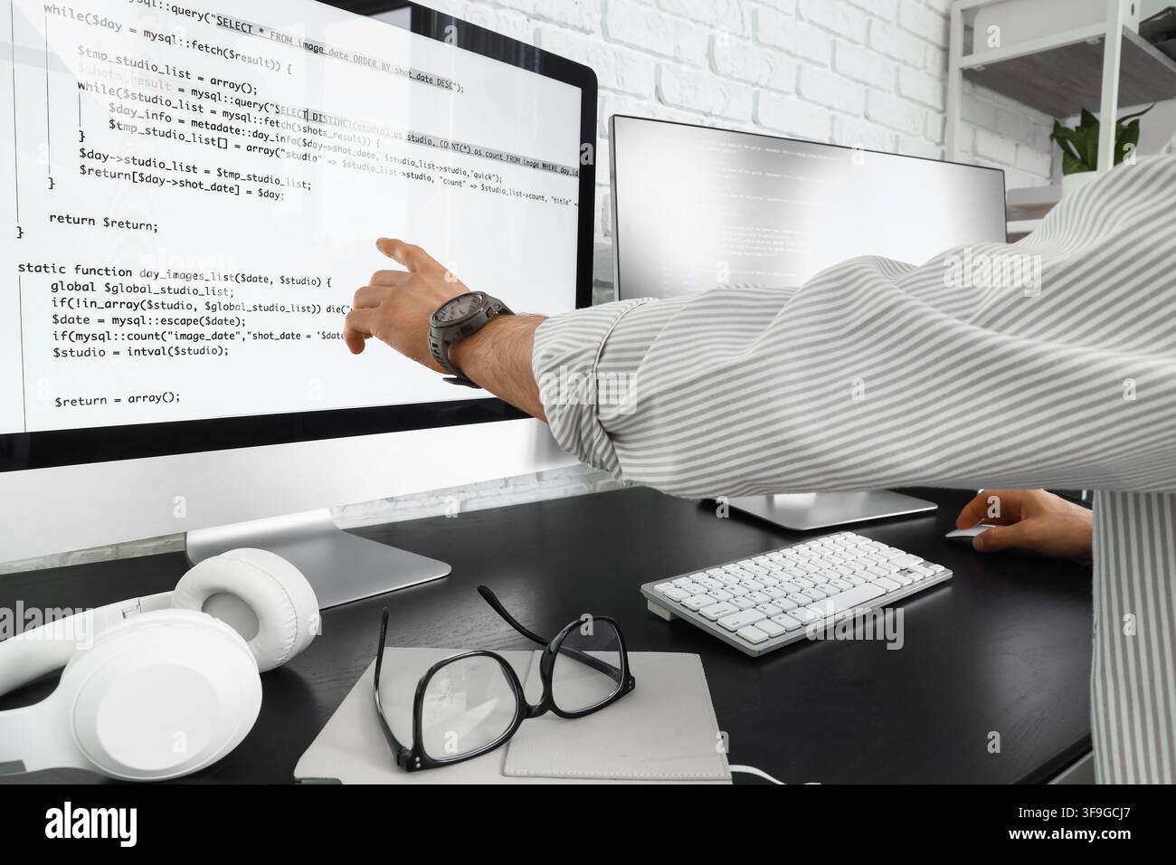 Programmierer zeigt auf einen Computerbildschirm mit Code, Softwareentwicklung und Webprogrammierungskonzept, moderner Bürorbeitsplatz Stockfoto