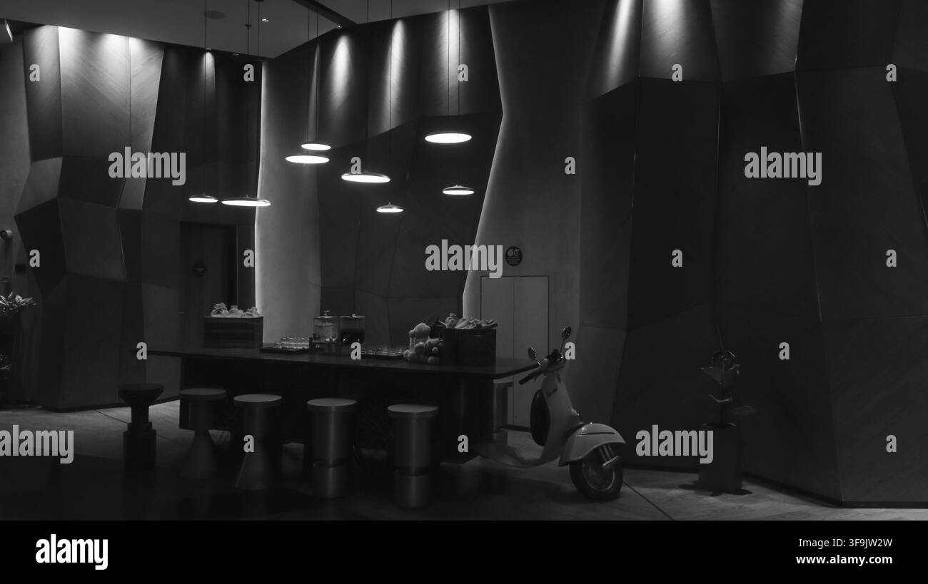 Monochromes Modernes Luxus-Hotel-Lobby-Interieur mit geometrischer Holzvertäfelung und Vintage-Scooter Stockfoto