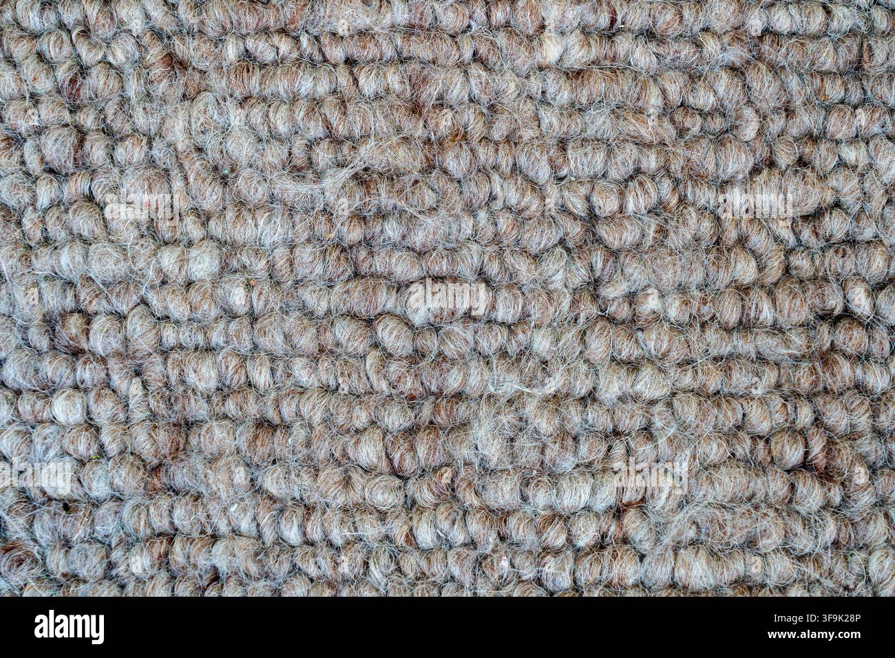 Nahaufnahme von strukturiertem beige und braunem Boucle-Stoff mit weichen Naturfasern und einer kuscheligen gewebten Oberfläche, abstrakter Textilhintergrund für Innendesign Stockfoto