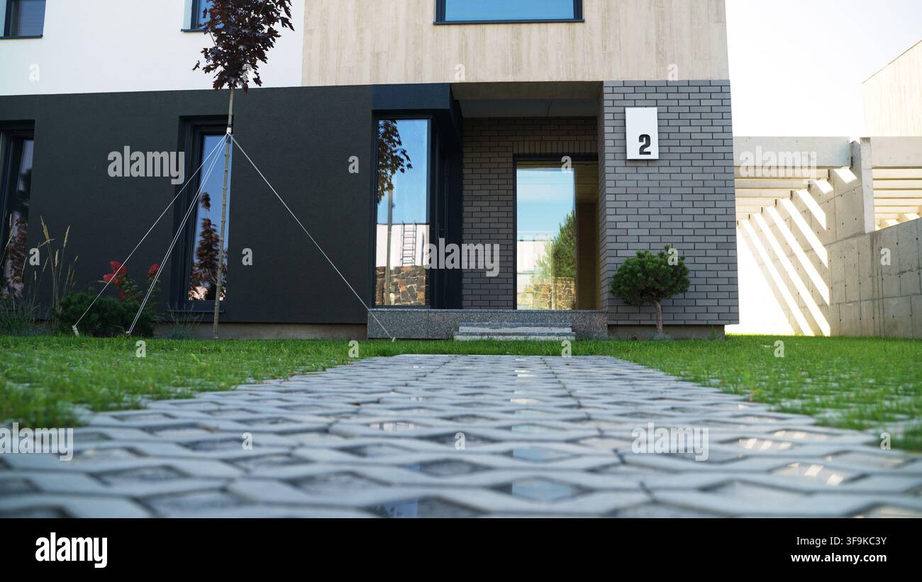 Moderne Hausfassade zeigt minimalistisches Wohndesign, grünen Rasen und Eingangsweg Stockfoto