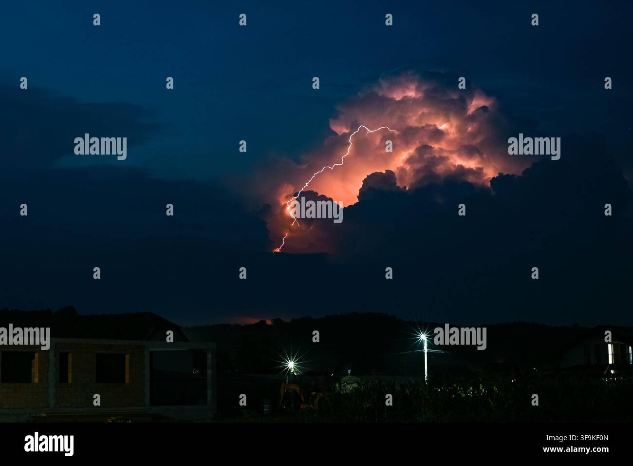 Ein Blitzschlag trifft den Boden von der Spitze einer hoch aufragenden Gewitterwolke Stockfoto