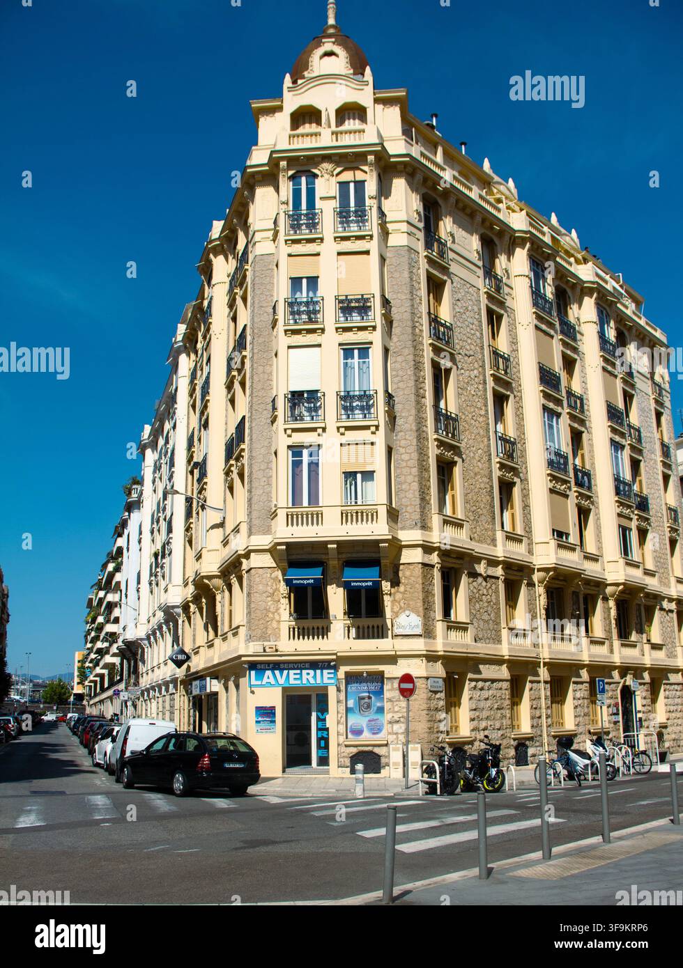 ein klassisches Eckwohnhaus im französischen Stil mit verzierten Balkonen und dem Schild "Laverie" im Erdgeschoss Stockfoto