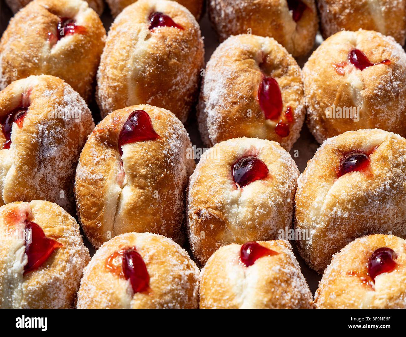 Leckere selbstgemachte Marmeladen-Donuts, die mit fruchtiger Marmelade triefen und mit einer großzügigen Schicht Zucker überzogen sind Stockfoto