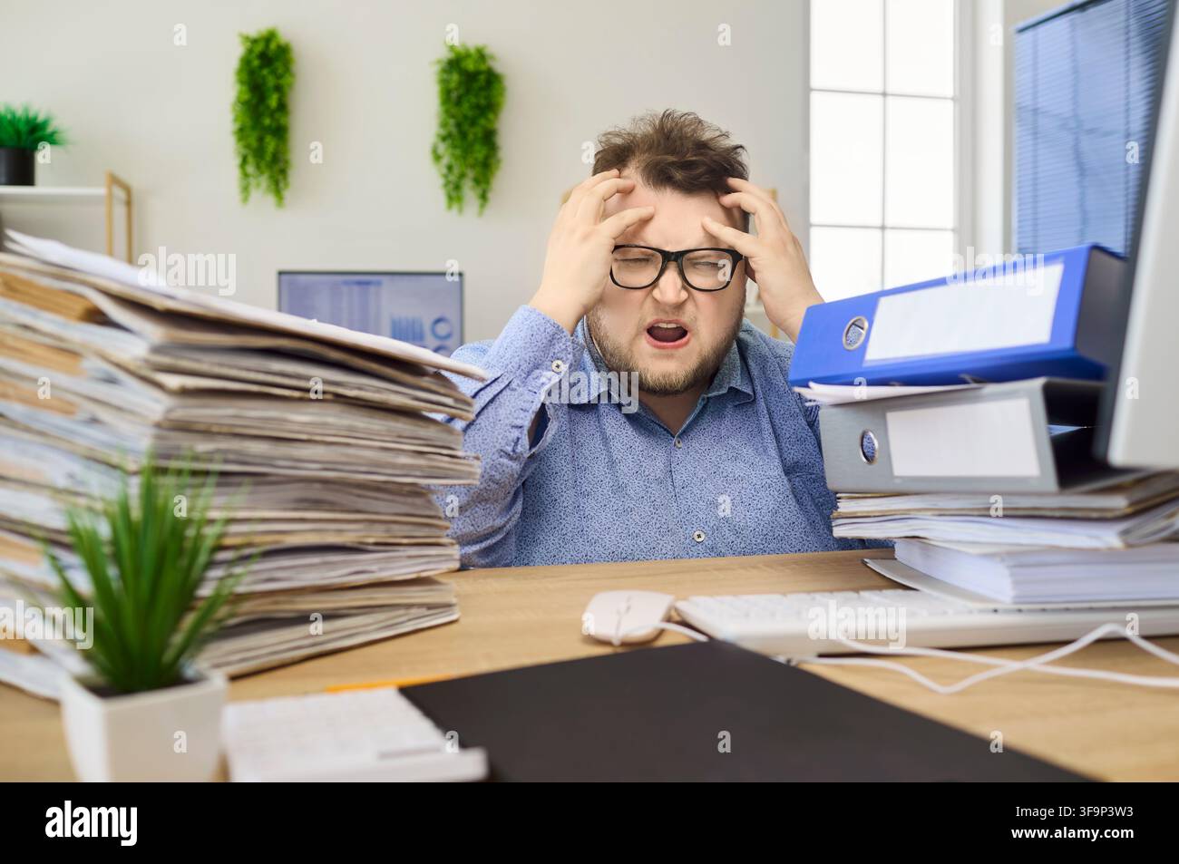 Gestresster Buchhalter, überwältigt von Papierkram und Fristen am Büroarbeitsplatz Stockfoto