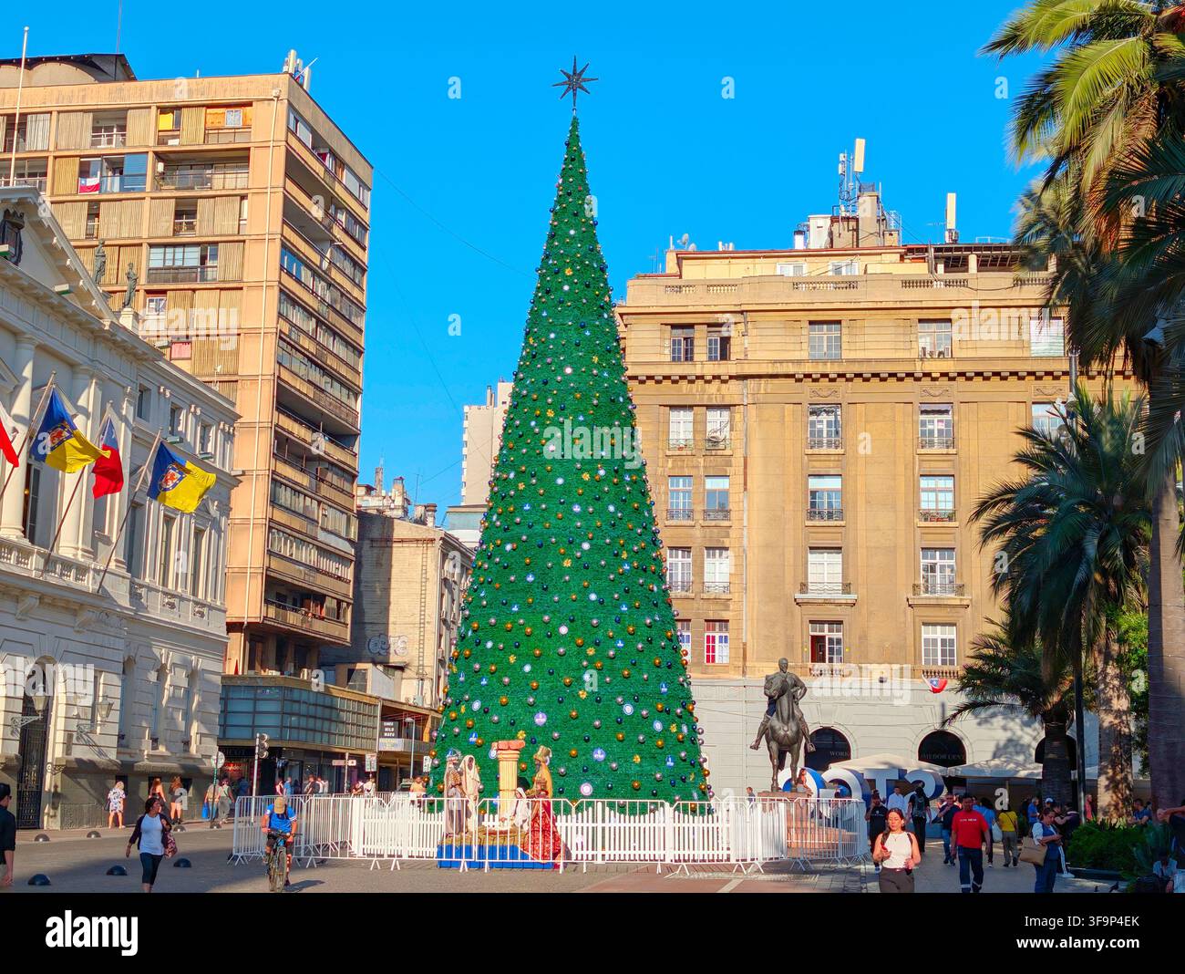 SANTIAGO, CHILE - 03. DEZEMBER 2025: Ein hoher geschmückter Weihnachtsbaum steht auf dem Plaza de Armas-Platz, umgeben von historischen Gebäuden und Palmen in San Stockfoto