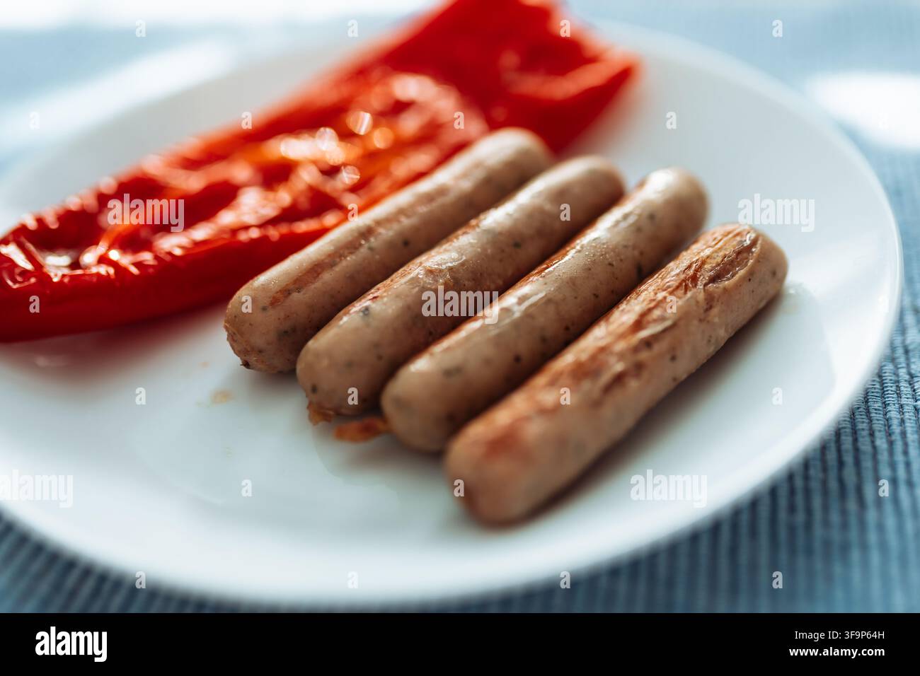 Gegrillte Würste mit gerösteter roter Paprika auf weißem Teller Stockfoto