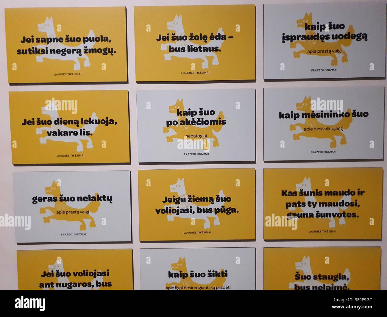 Eine Darstellung von zwölf rechteckigen Paneelen, die in einem 3x4-Raster auf einer weißen Wand angeordnet sind. Jedes Panel zeigt eine stilisierte weiße oder gelbe Hundesilhouette mit Stockfoto