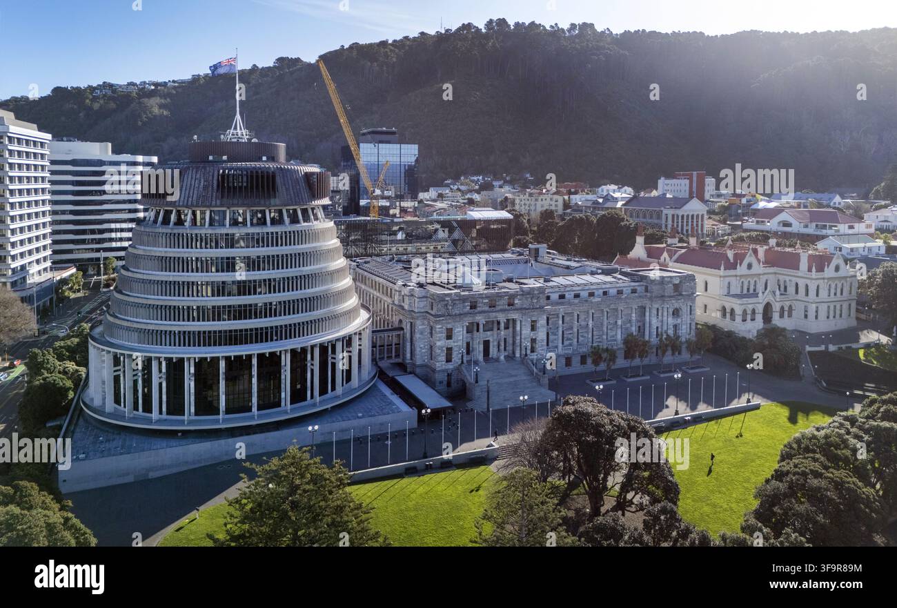 Luftaufnahme des Beehive und des Parlamentsgebäudes, umgeben von üppigen grünen Rasenflächen und städtischen Gebäuden in Wellington, Wellington Region, Neuseeland. Stockfoto