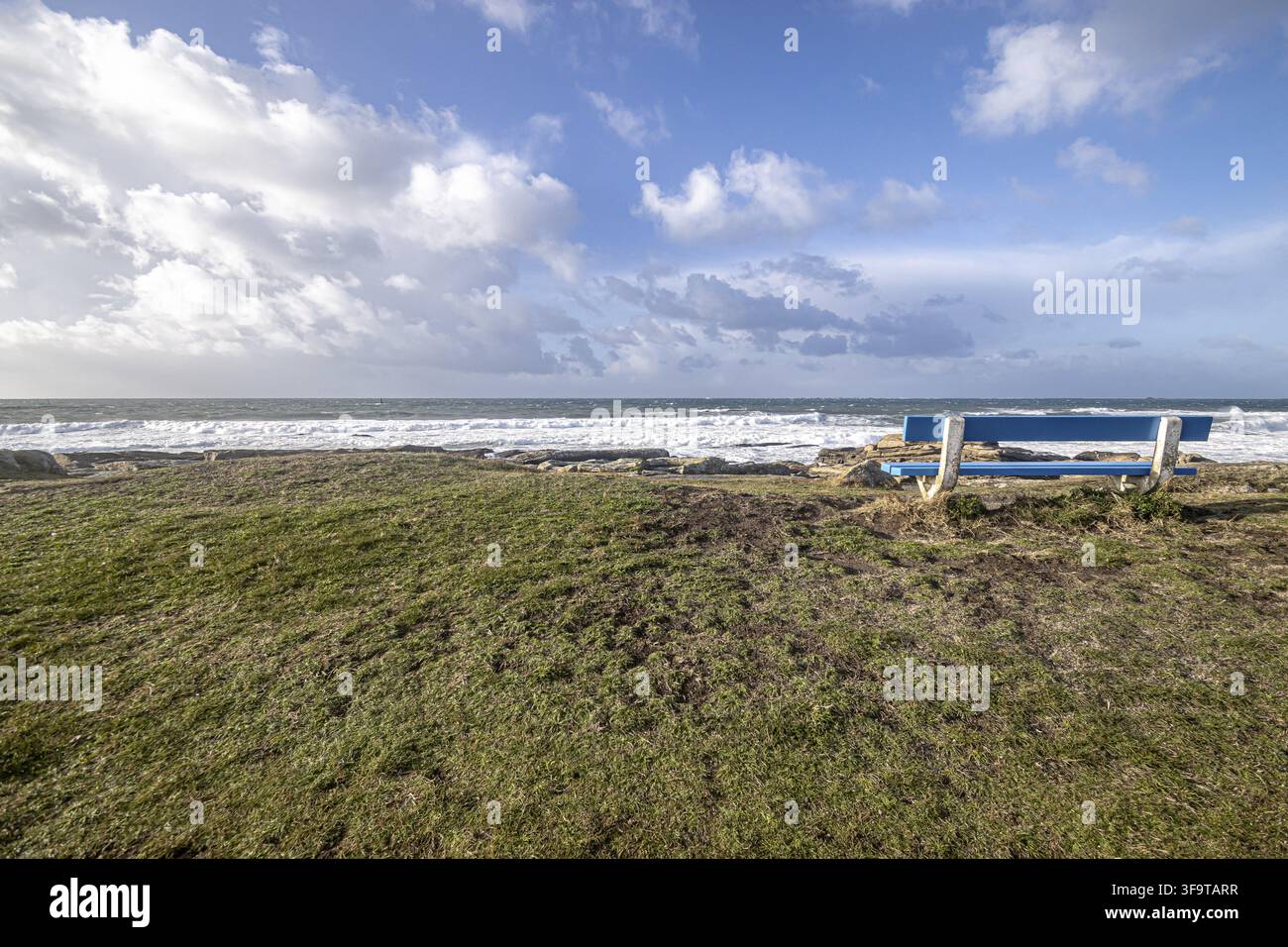 Mächtige Atlantikwellen schlagen gegen felsige Klippen entlang der Küste der Bretagne in Frankreich. Unter einem strahlend blauen Sommerhimmel glitzern das Meer und die schroffe Küste Stockfoto