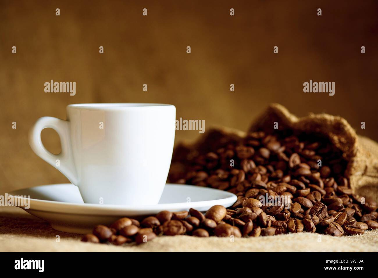 Weiße Tasse und Kaffeebohnen auf einem unscharfen Hintergrund Stockfoto