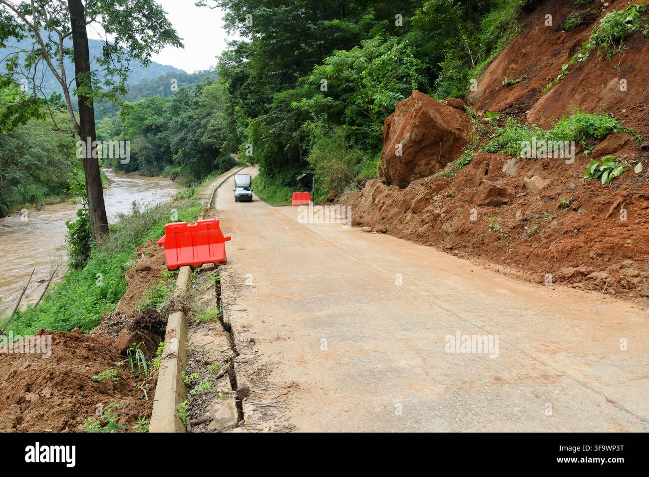 Eine Bergstraße tropischer Wald Erdrutsch Fluss Betonbarriere unbefestigte Straße Bergstraße tropischer Wald Erdrutsch Fluss Betonbarriere unbefestigte Straße Stockfoto
