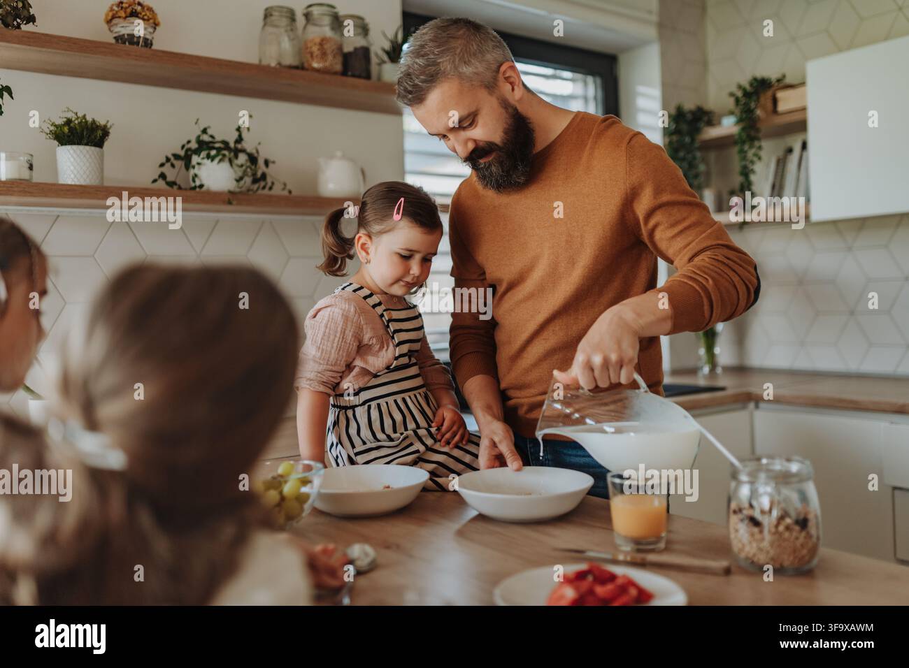 Vater bereitet das Frühstück für die Töchter vor der Schule zu. Stockfoto