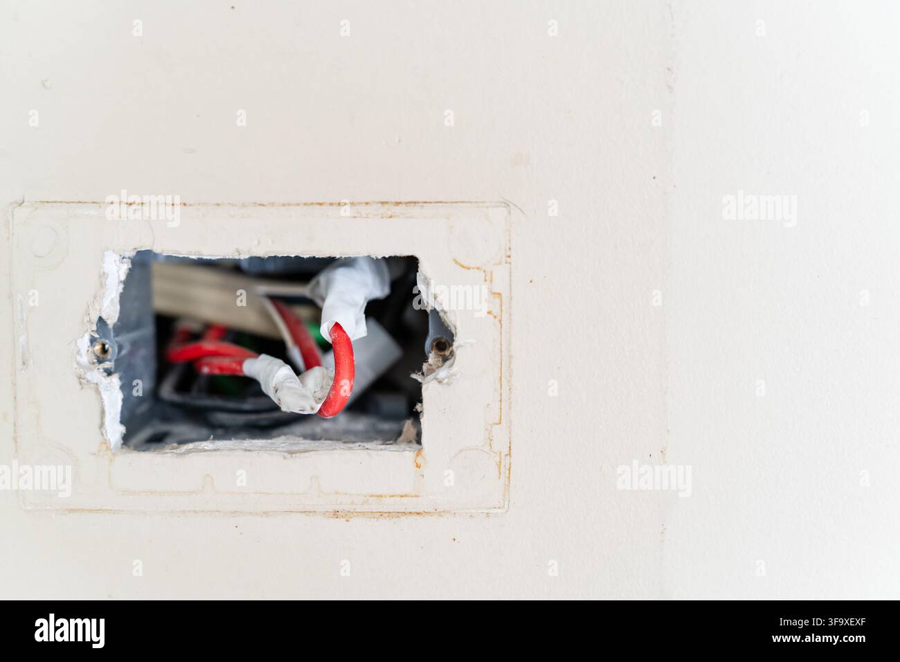 Freigelegte elektrische Leitungen in einer kaputten Wandsteckdose Stockfoto