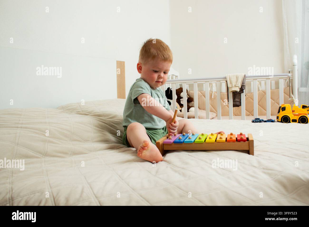 Der zweijährige Junge spielt zu Hause Xylophon. Das Antippen farbenfroher Tasten fördert die Feinmotorik und das musikalische Ohr. Frühkindliche Erziehung durch Rhythmus Stockfoto