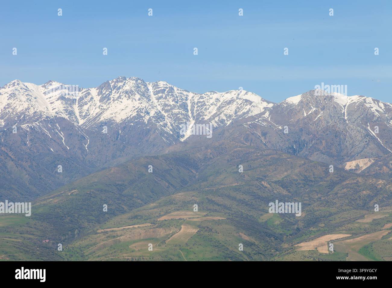 Schneebedecktes Gebirgsmassiv über grüntem Agrartal Stockfoto