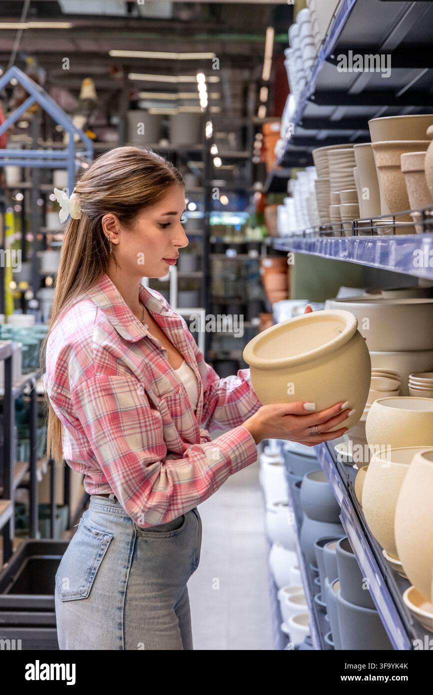 Frau wählt einen großen Pflanzkübel in einem Einzelhandelsgeschäft aus. Einkaufen für Heim- und Gartendekoration. Stockfoto