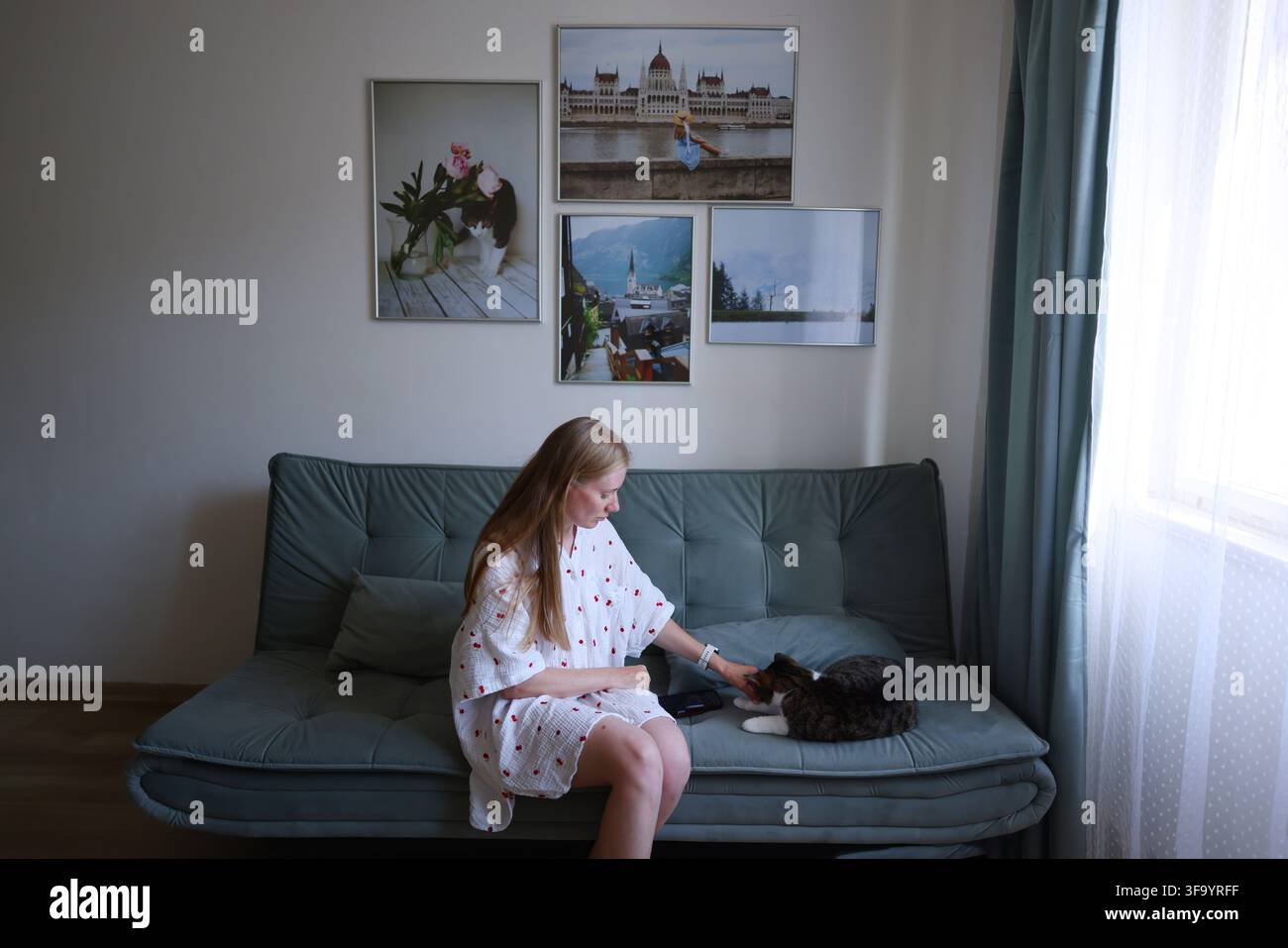 Junge Frau verwendet Silikon-Aufsitzer beim Entspannen zu Hause mit ihrer Katze, Gehörschutz und friedliches Ruhekonzept. Stockfoto