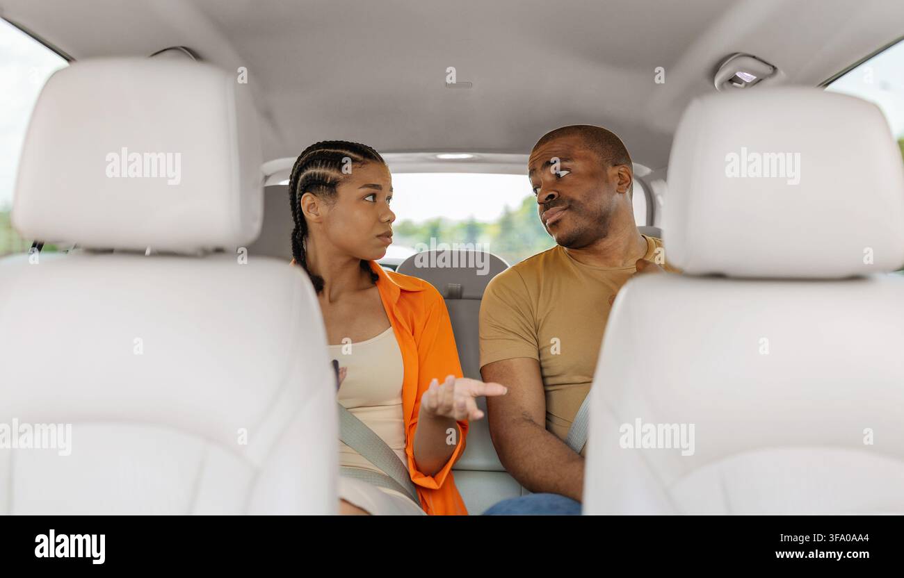 Junges schwarzes Paar führt ein ernstes Gespräch, während es im Auto sitzt Stockfoto