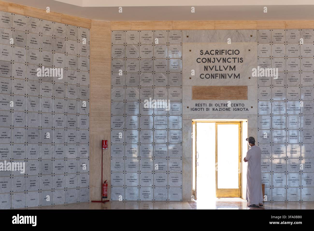 Ansicht des italienischen Friedhofs am Al-Alamein-Kriegsdenkmal mit Marmorwänden, auf denen die Namen von Soldaten eingraviert sind, und einem Mann, der am Eingang in Al Al steht Stockfoto