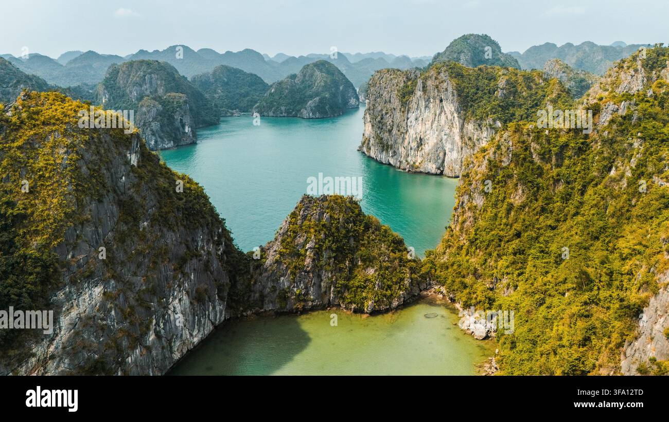 Luftaufnahme von nebligen Kalkstein-Karstinseln, die mit üppiger Vegetation bedeckt sind, über türkisblauem Wasser in der Lan Ha-Bucht, Cat Ba-Archipel, Hai Phong, Vietnam. Stockfoto