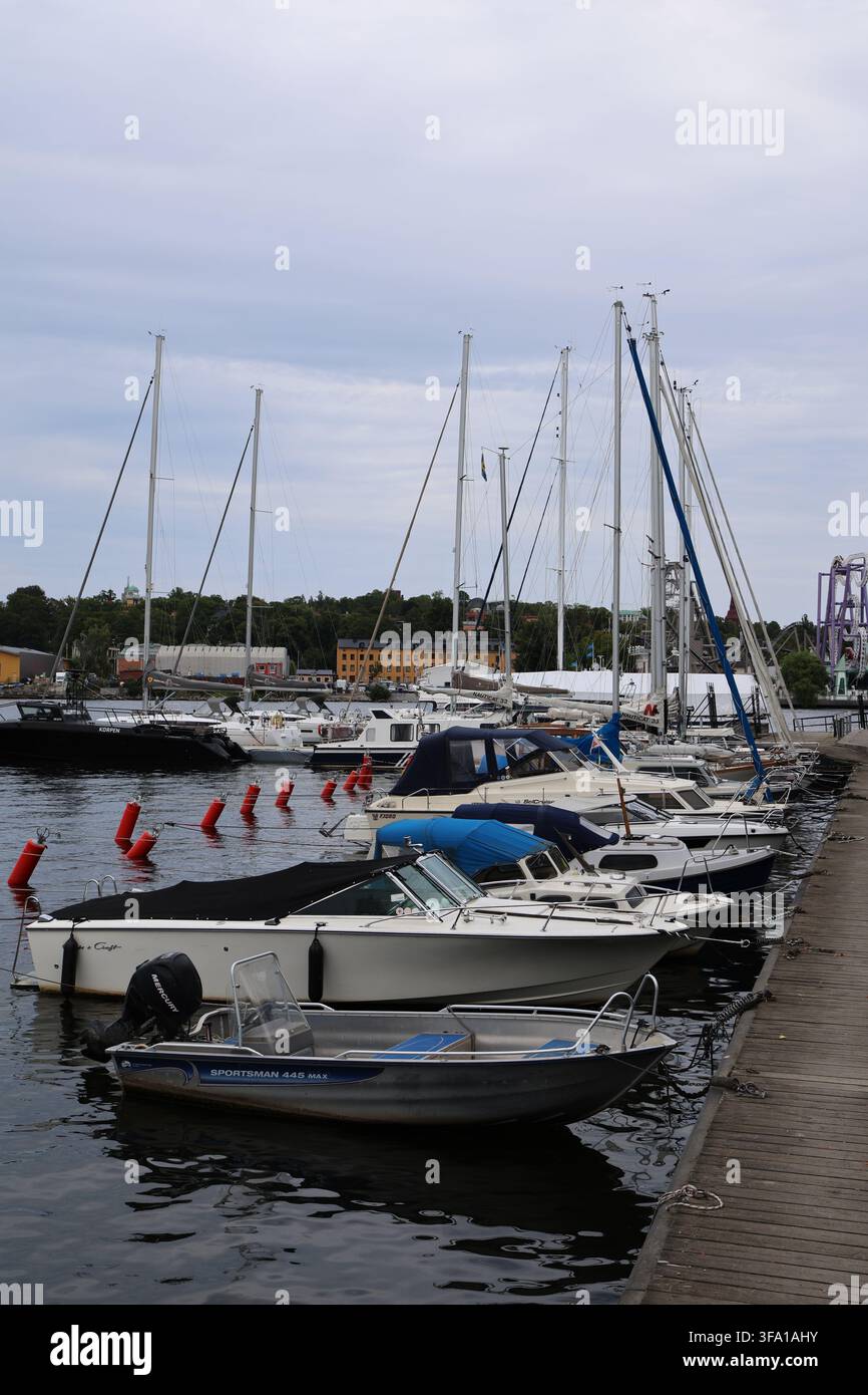 Kleine Boote, die am Kai von Skeppsholmen in Stockholm, Schweden, festgemacht sind, mit dem Ufer und dem ruhigen Wasser in der Nähe. Stockfoto