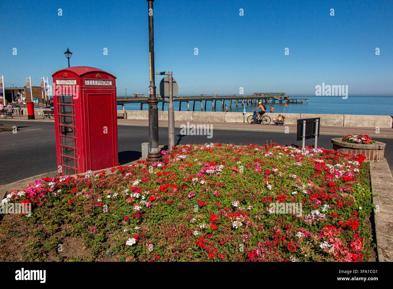 Geranien und eine rote Telefonzelle mitten an einer Kreuzung am Seefront außerhalb des King's Head Pubs in Deal, Kent mit dem Pier. Stockfoto