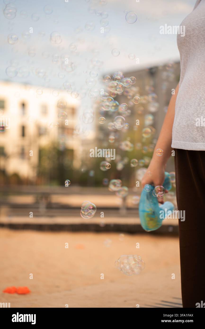 schillernde Seifenblasen, die durch eine sanft verschwommene Außenszene schweben, im warmen Sonnenlicht leuchten mit pastellfarbenen Reflexionen, cremigem Bokeh und einem träumerischen Stockfoto