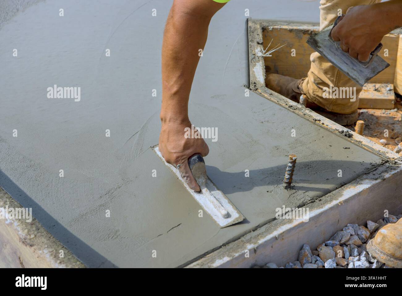 Maurer arbeitet an den letzten Schliff auf der neu gegossenen Betonplatte auf der Baustelle Stockfoto