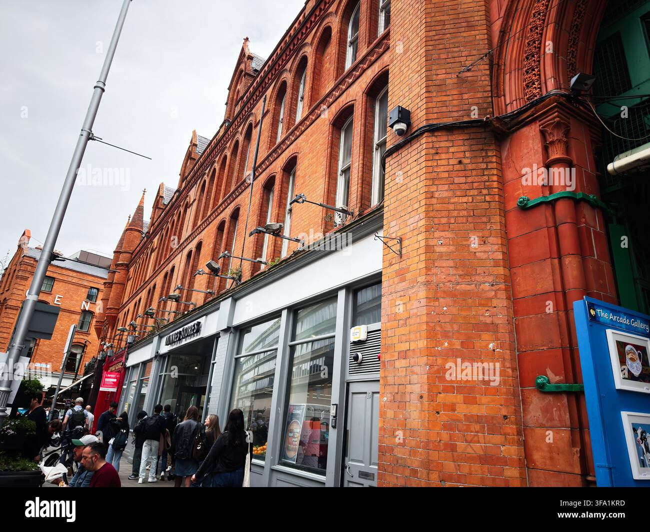 Dublin, Irland – 22. Mai 2026: Belebte Dubliner Straße mit roten Backsteinfassaden aus der viktorianischen Ära, Geschäften und Fußgängern im städtischen Stadtzentrum. Stockfoto