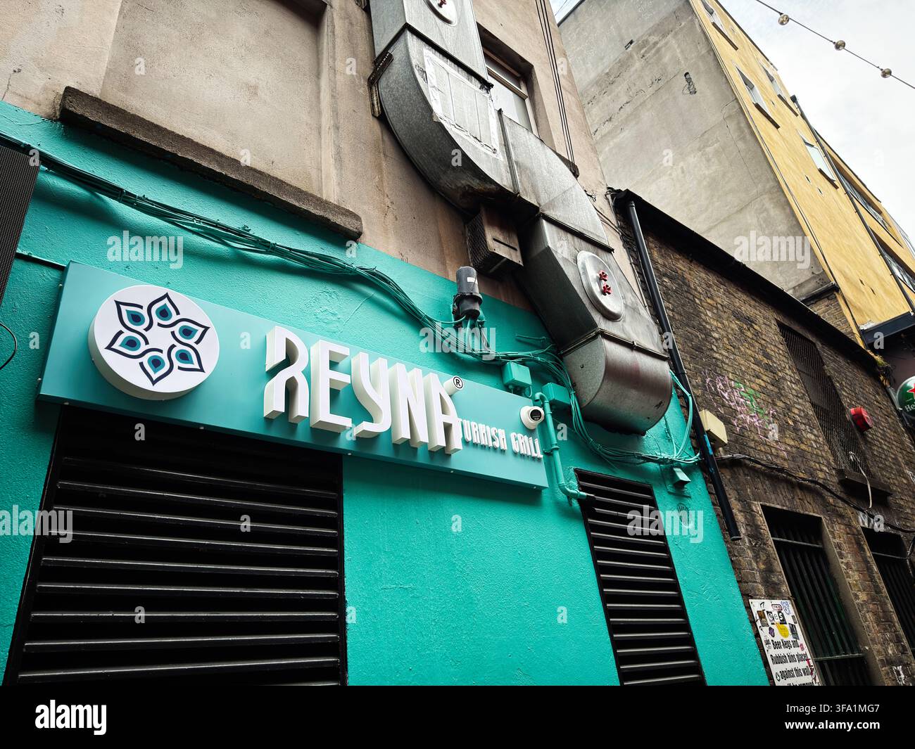 Dublin, Irland – 22. Mai 2026: Ein türkisfarbenes Restaurantschild und Metall-Lüftungsrohre rahmen die raue Außenseite einer Gasse in Dublin, Irland, ein. Stockfoto