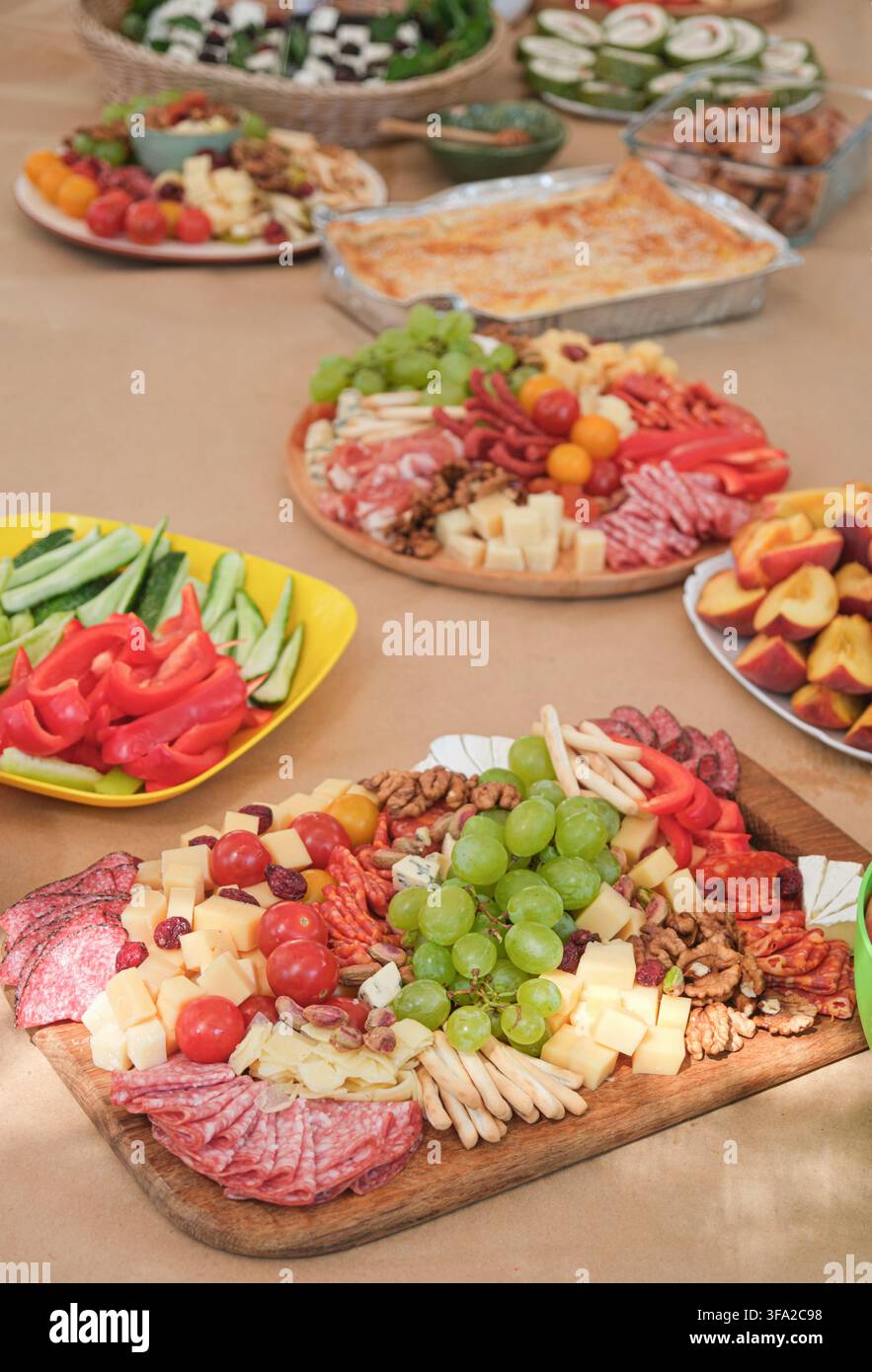 Festlicher Buffettisch mit einer großen Platte mit Aufschnitt, frischem Gemüse, Obst, Käse und verschiedenen Vorspeisen, vorbereitet für eine Essensparty Stockfoto