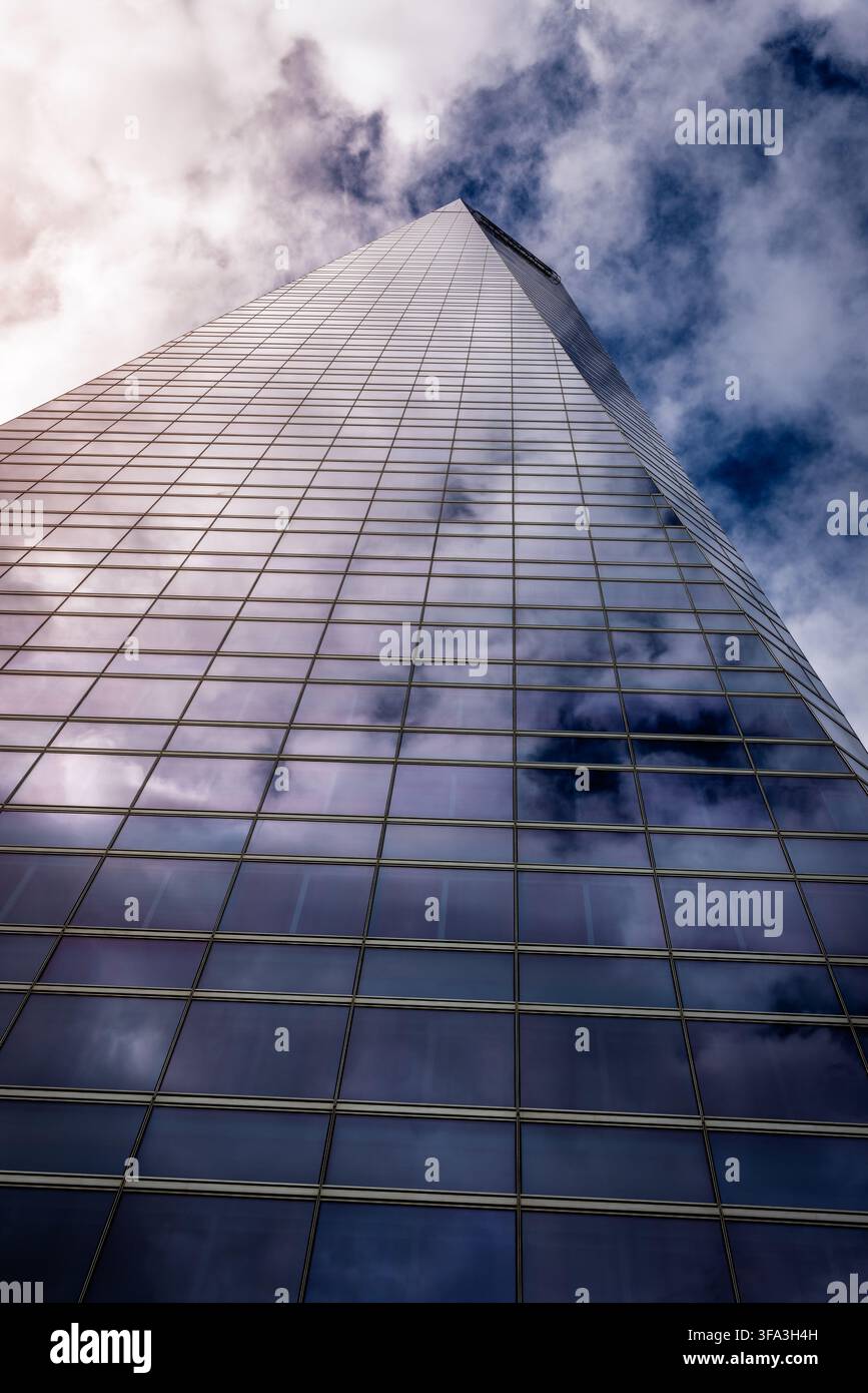 Niedrigwinkelaufnahme einer reflektierenden Glasfassade eines Wolkenkratzers mit in den Fenstern gespiegelten Wolken Stockfoto