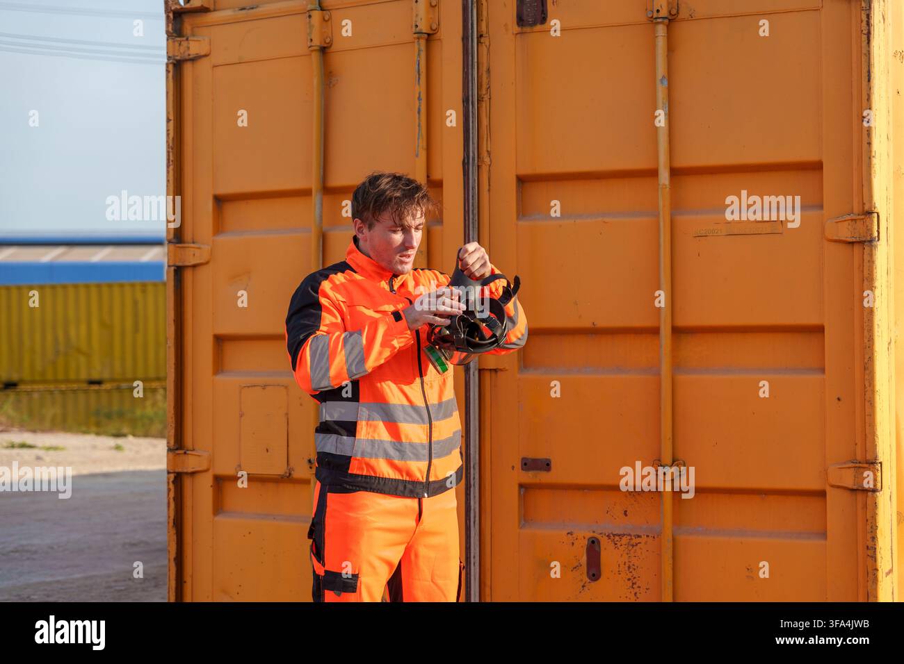 Bauarbeiter in Warnkleidung bereitet Sicherheitsausrüstung im Freien an einer Lagerstätte vor. Ideal für Bauwesen, Sicherheitstrainings und oc Stockfoto