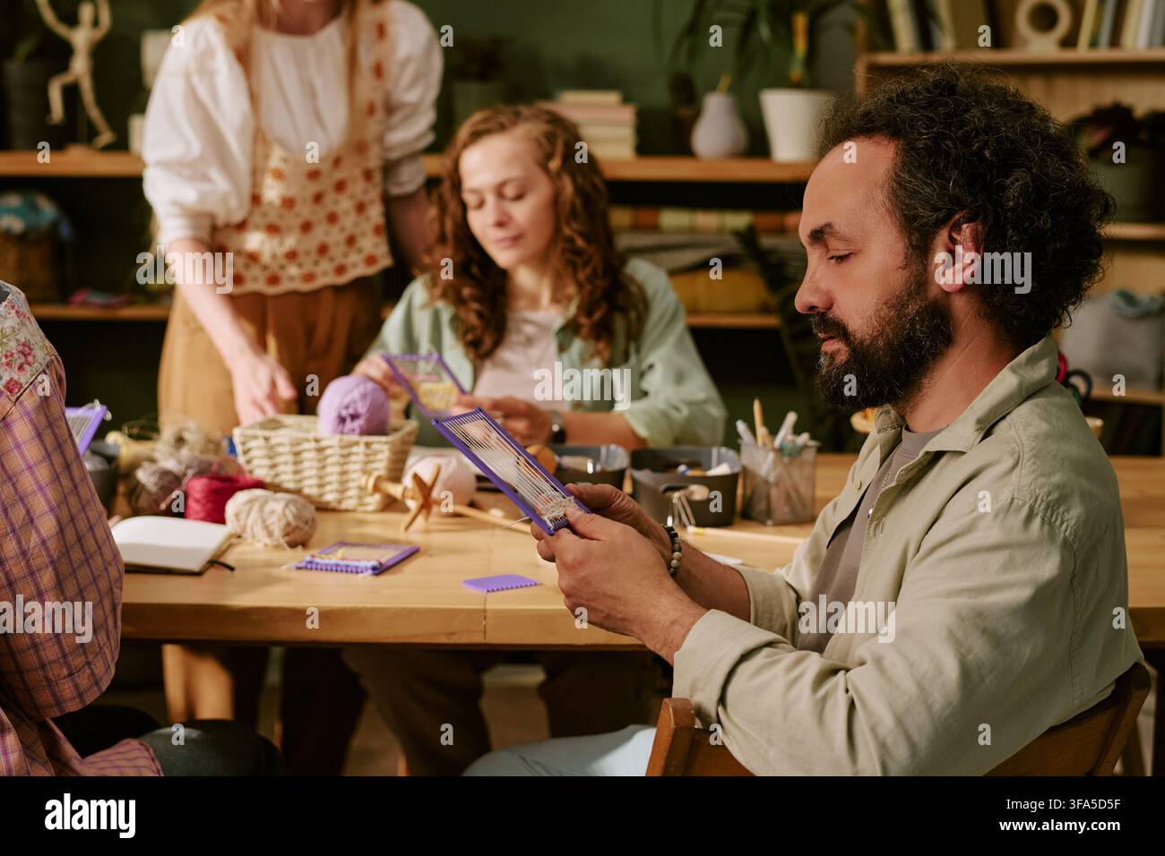 Kaukasischer Mann und Frau lernen Weben in einem kreativen Strickworkshop Stockfoto