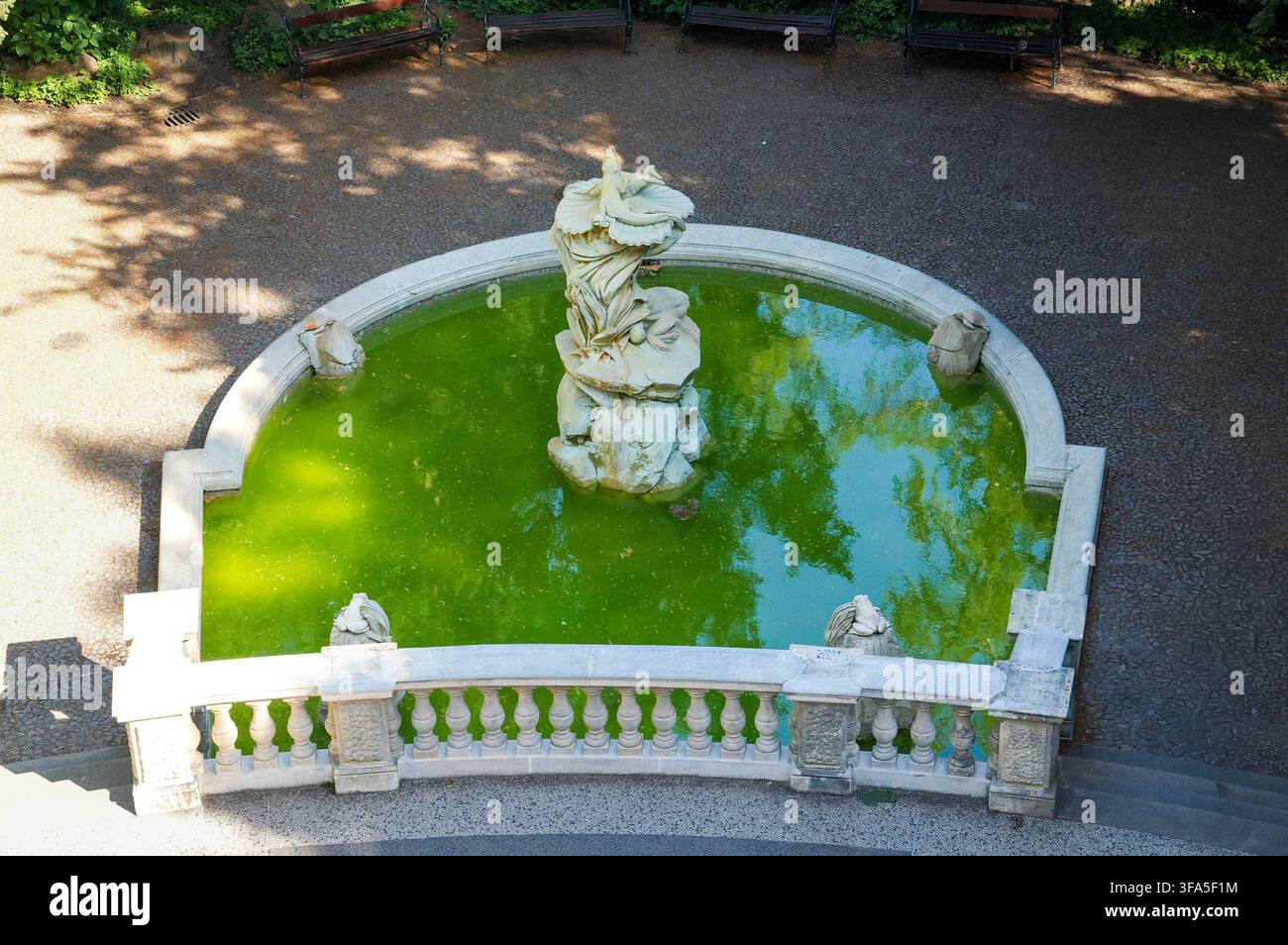 Luftaufnahme einer historischen Steinfontäne mit Skulptur und grünem Wasser in einem europäischen Park Stockfoto