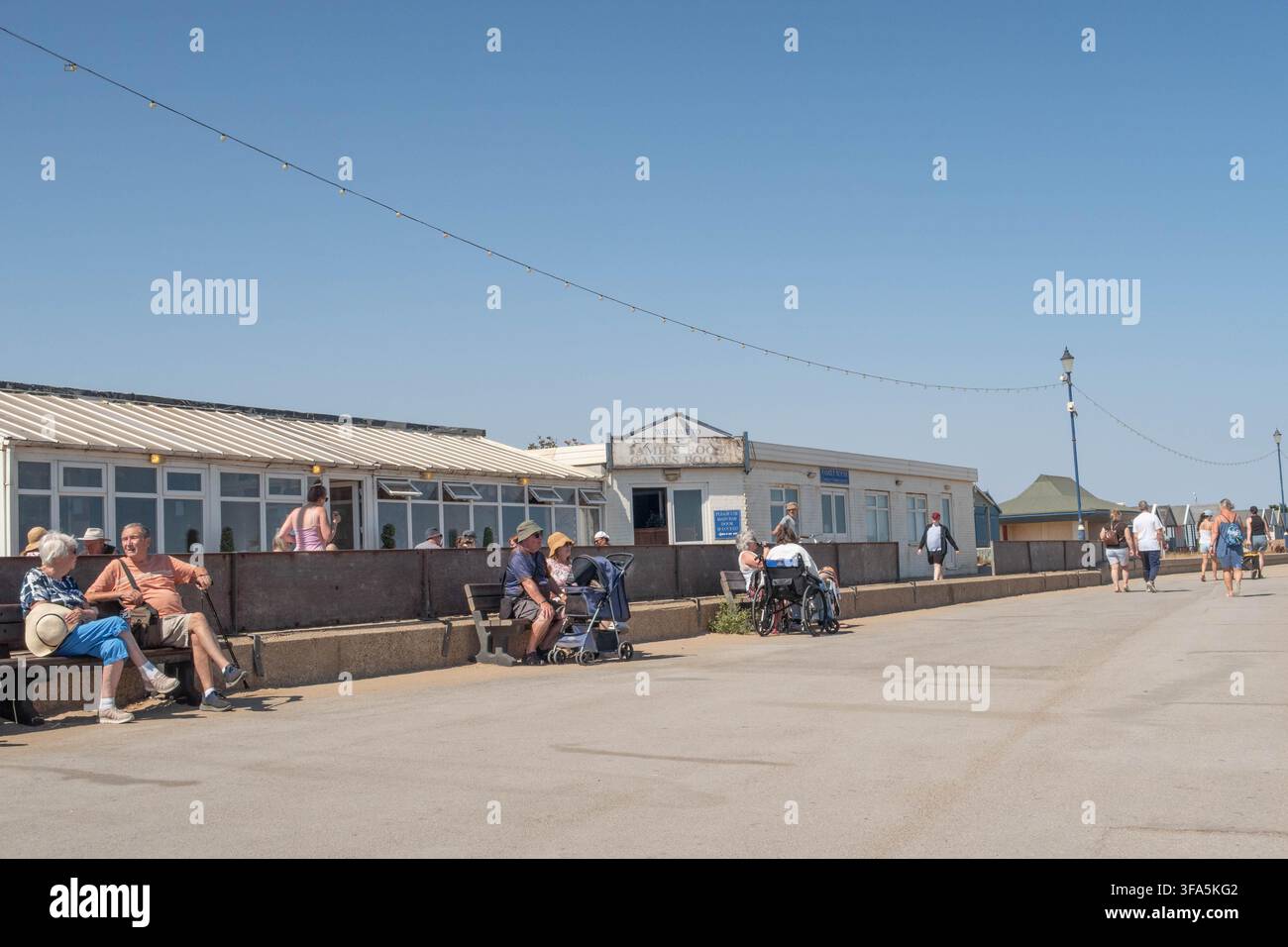 Menschen, die auf der Promenade am Strand von Sutton-on Sea, Lincolnshire, im heißen Sommer 2026 entspannen Stockfoto
