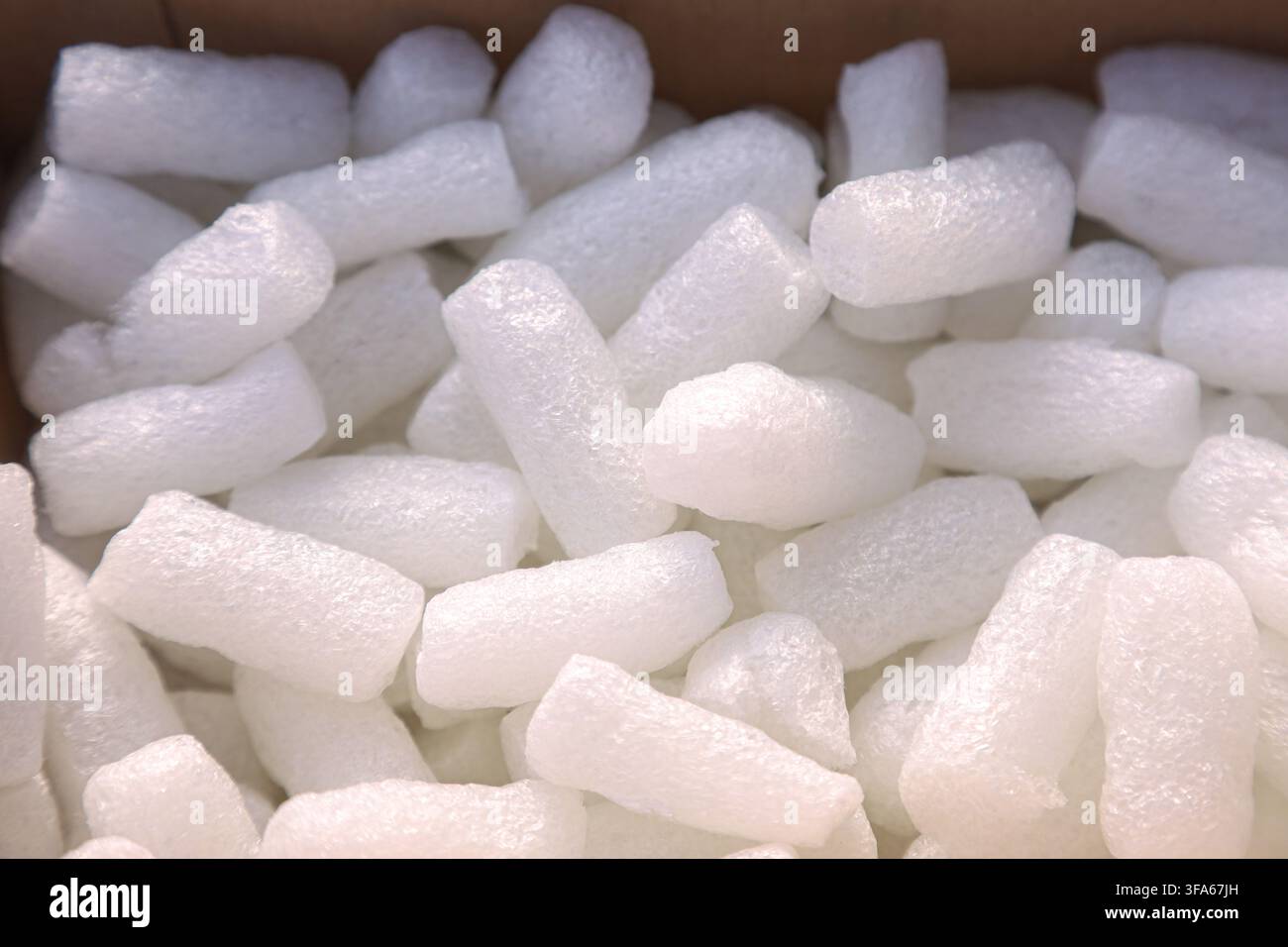 Nahaufnahme von weißen expandierten Polystyrol-Schaumstücken und Schutzverpackungsmaterial, die in einem Kartonversandkarton gestapelt sind. Stockfoto