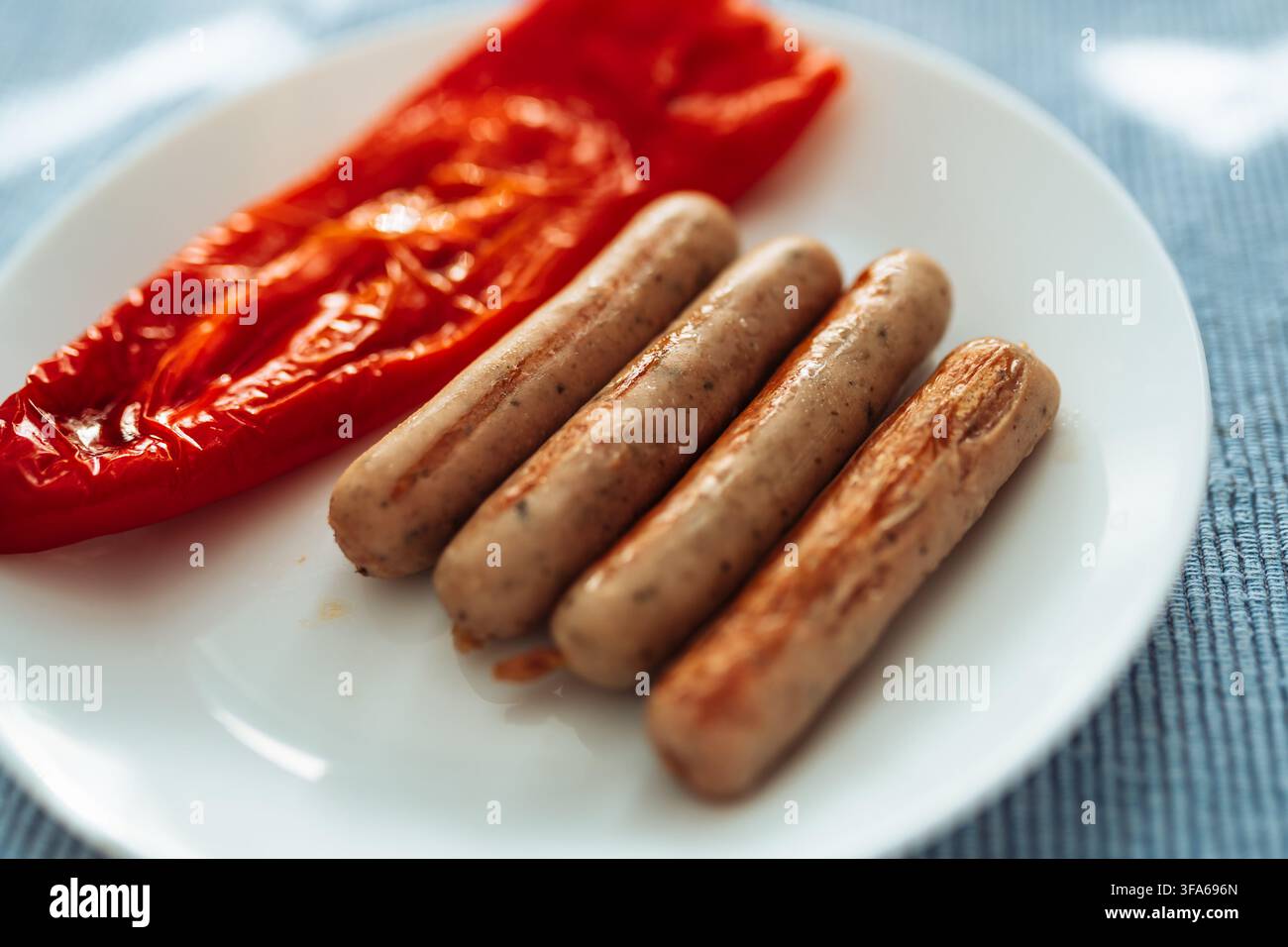 Gegrillte Würste mit gerösteter roter Paprika auf weißem Teller Stockfoto