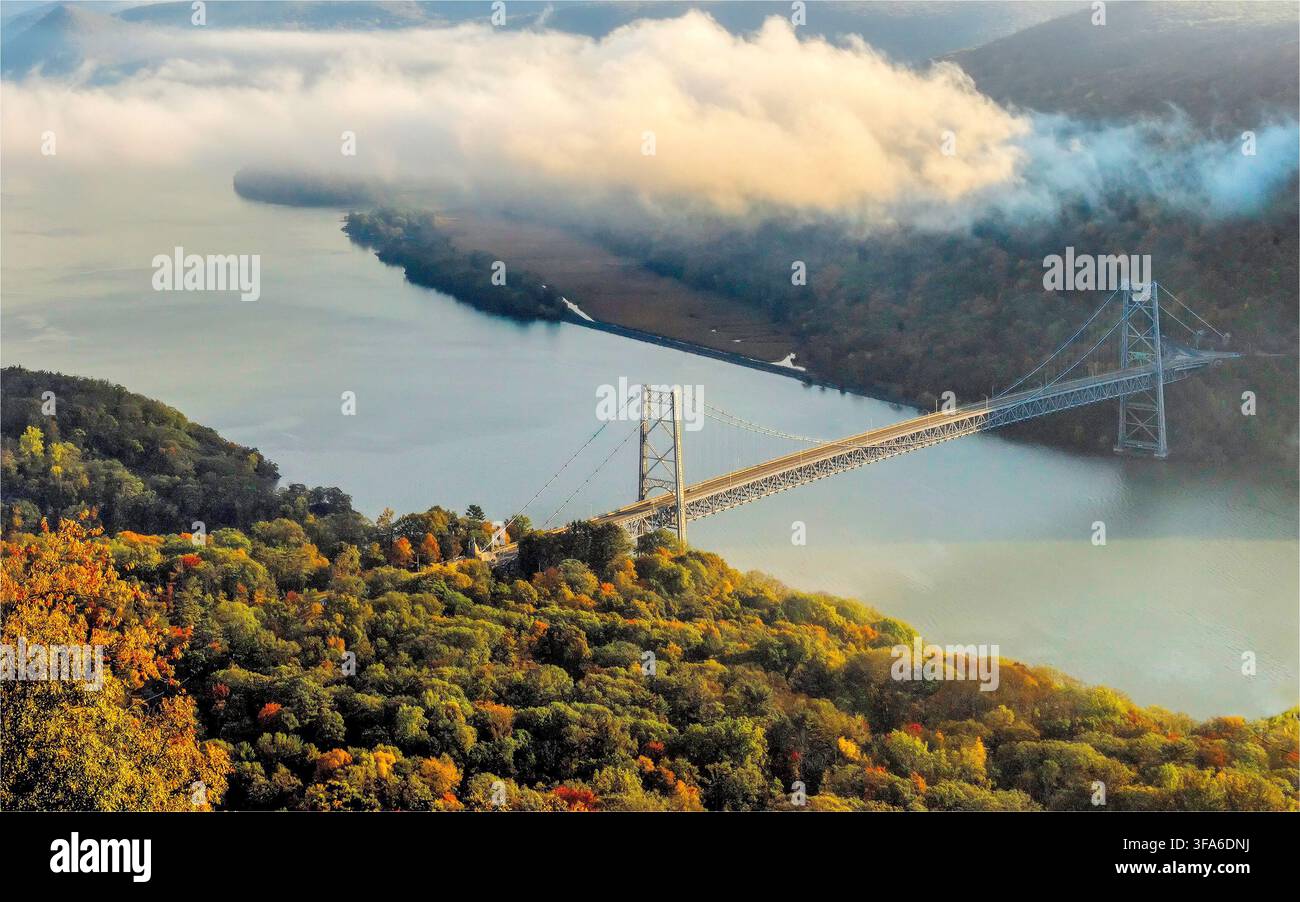 Luftaufnahme von Bear Mountain mit einer Brücke, die die Berge in New York State im Herbst mit bunten Bäumen und flauschigen Wolken überquert Stockfoto