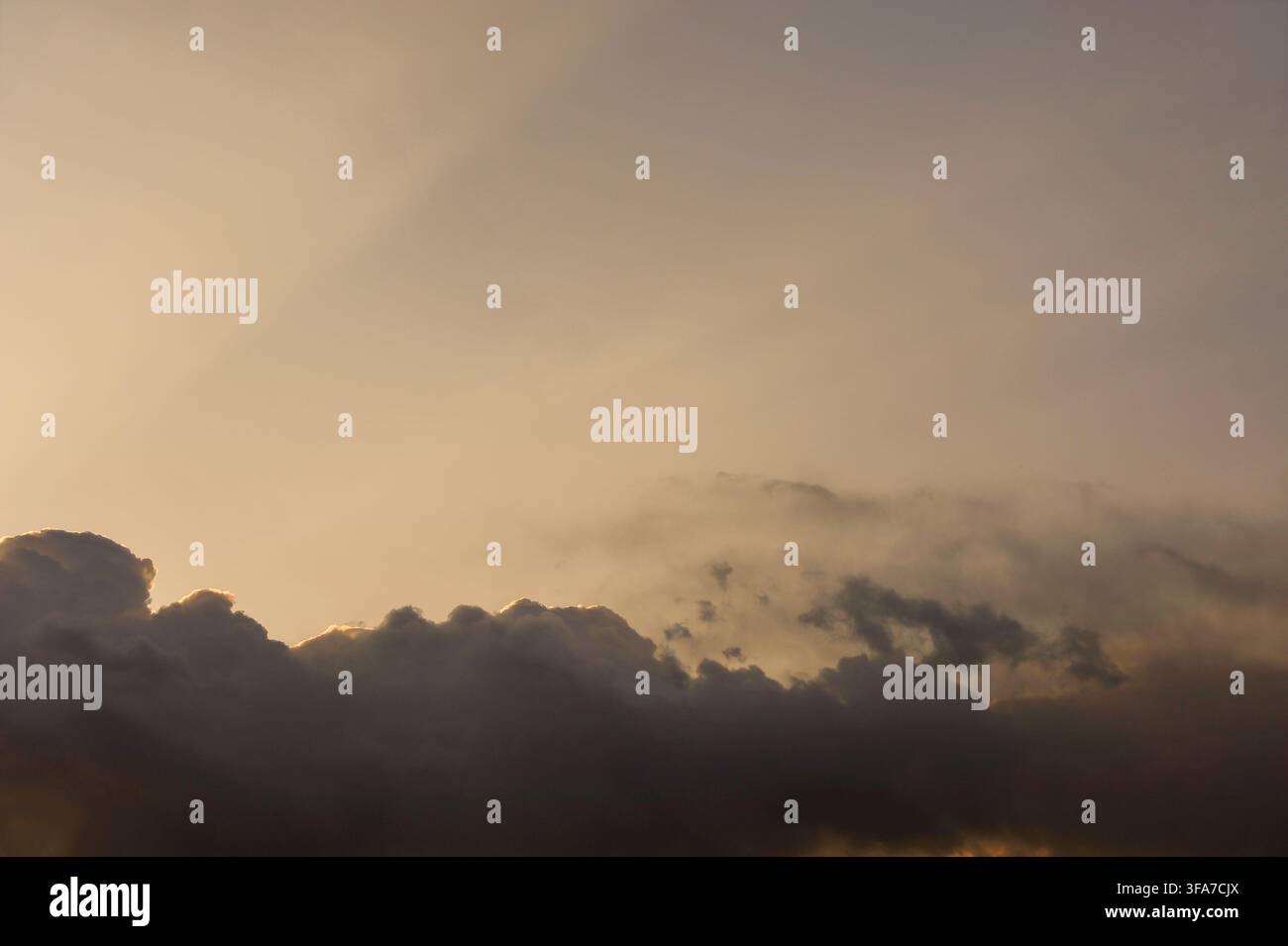 Dramatische dramatische Gewitterwolken, die entlang der Ränder von einem hellen goldenen Sonnenstrahl bei einem warmen Sonnenuntergang oder Sonnenaufgang beleuchtet werden. Stockfoto