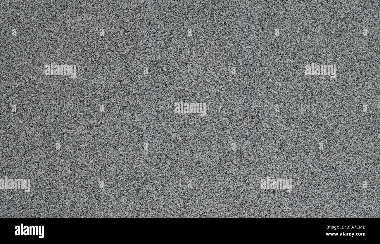 Horizontale Nahaufnahme einer polierten grauen Granitfläche mit schwarzen Sprenkeln, einem Salz-und-Pfeffer-Look und glatter, glänzender Steintextur Stockfoto