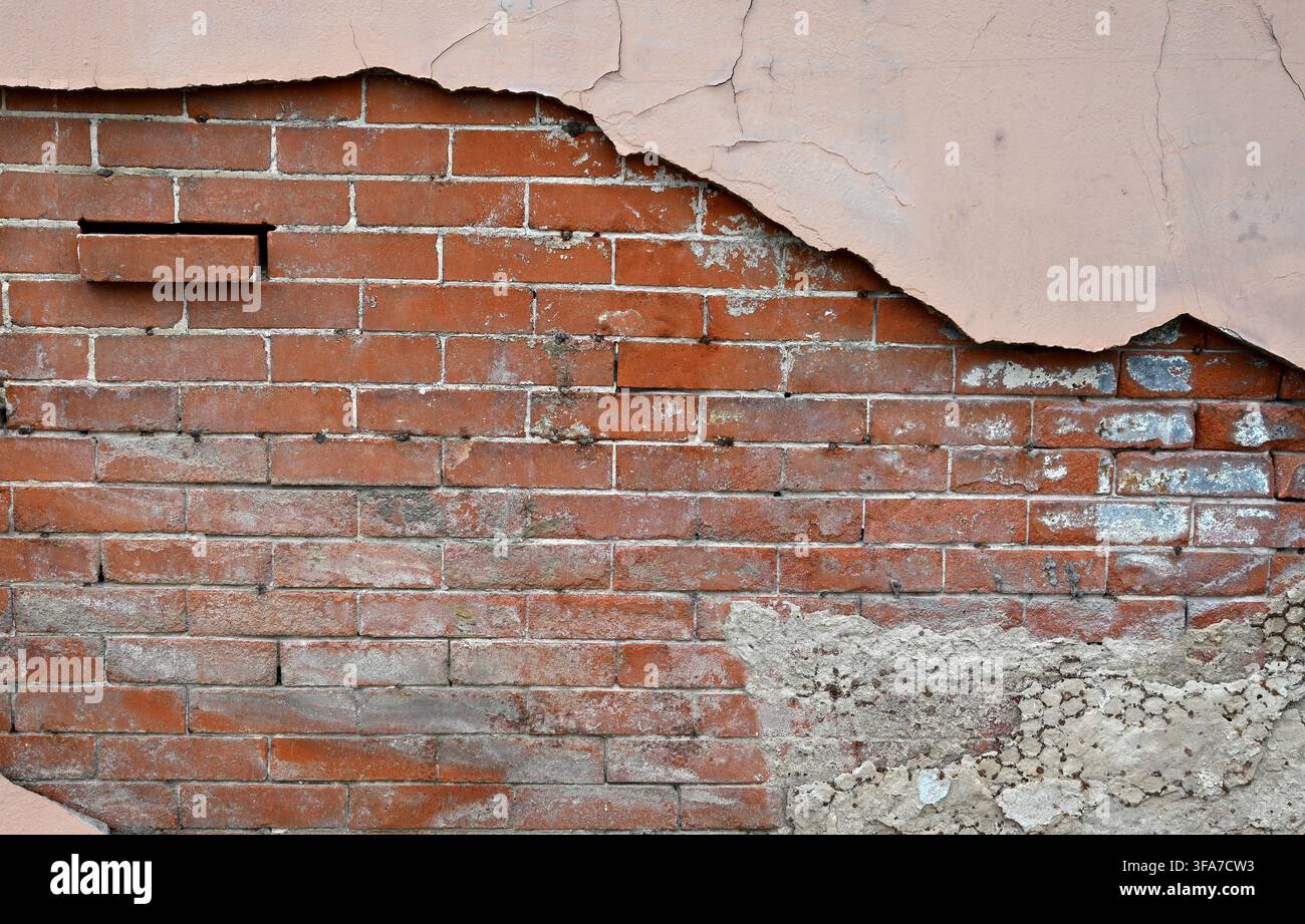 Horizontale Nahaufnahme einer sich zersetzenden mehrschichtigen Wandoberfläche mit hellbraun gestrichenem Beton, der sich ablöst Stockfoto
