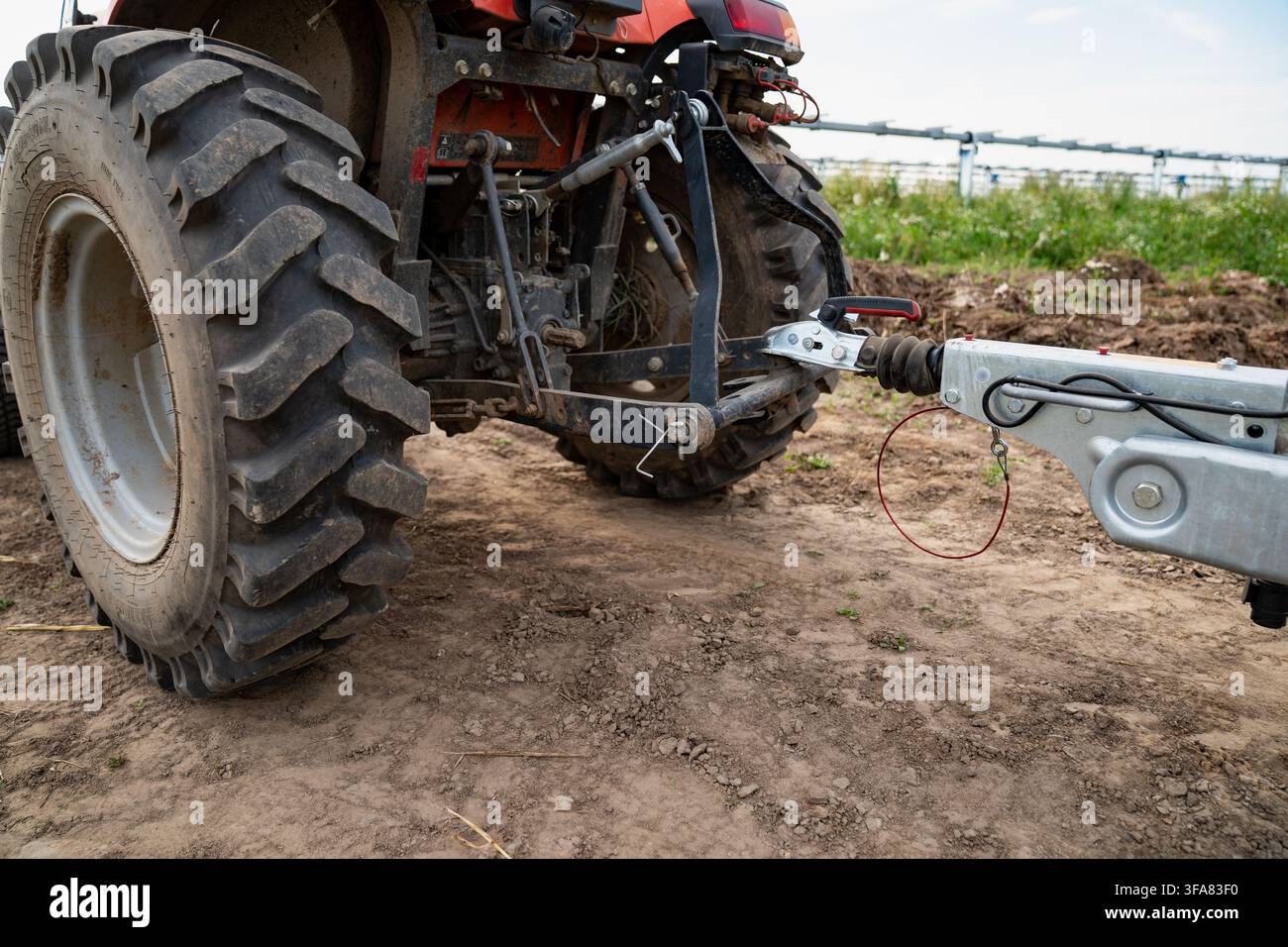 Ansicht der Hinterachse eines Traktors mit tief profiligen Agrarreifen, die an einer verzinkten Anhängerkupplung auf einer Erdbewegungsbaustelle montiert sind Stockfoto