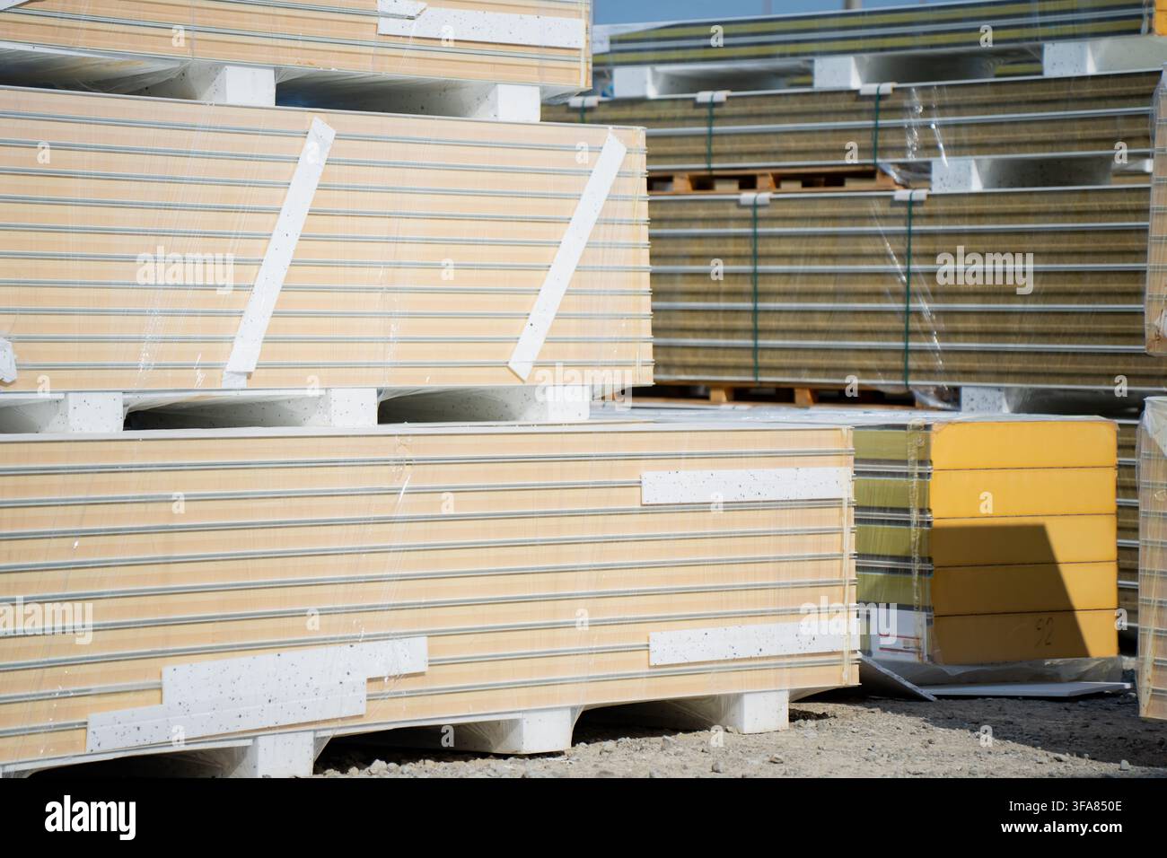 Vorgefertigte Verbund-Wandplatten mit Isolierung, die im Freien gestapelt sind und Wärmeeffizienz, industrielle Logistik und Baubeschaffung darstellen Stockfoto
