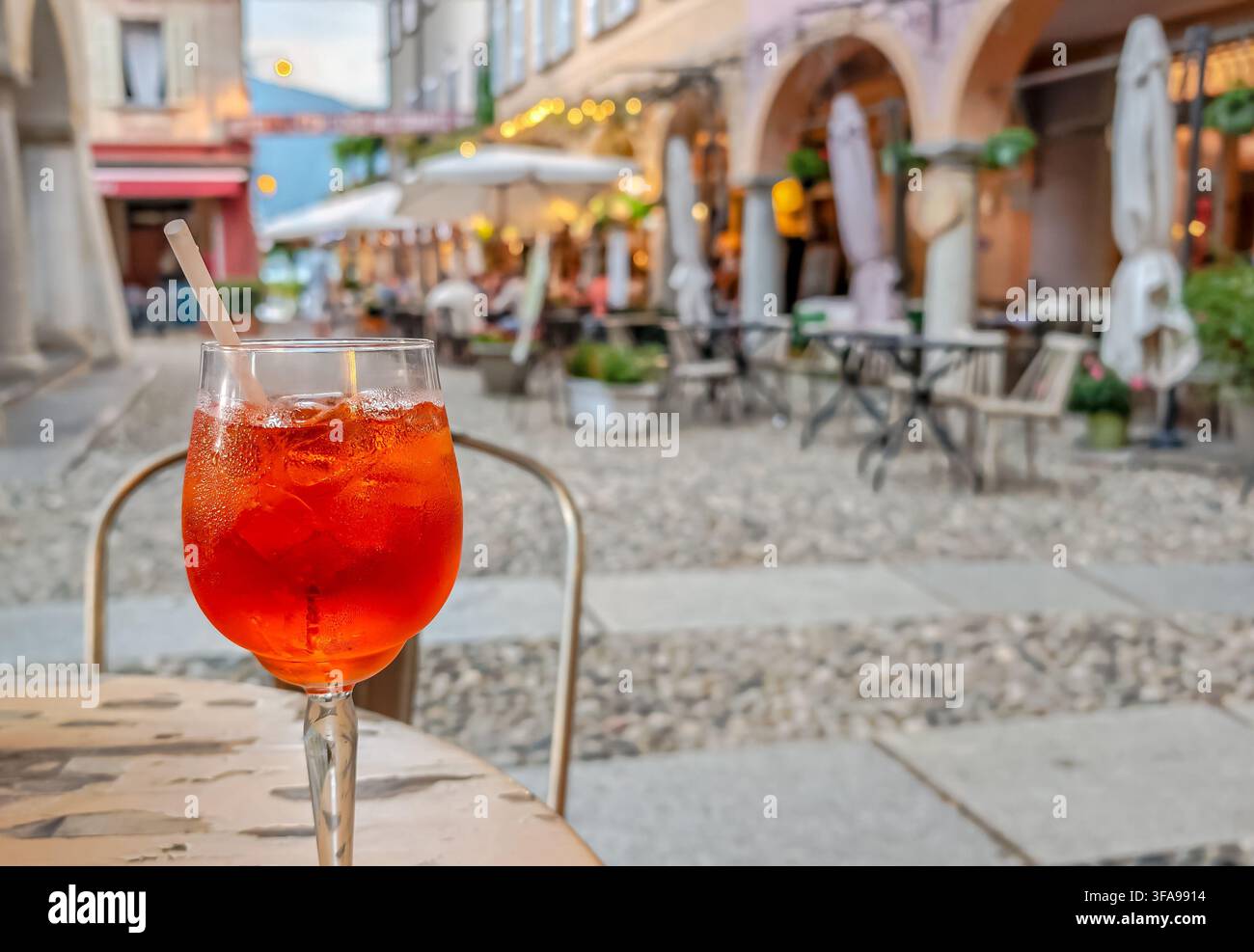 Traditionelles italienisches Aperitivo-Getränk, das auf einem Tisch serviert wird, mit einer bezaubernden historischen italienischen Stadt im Hintergrund, die authentische lokale Küche einfängt Stockfoto