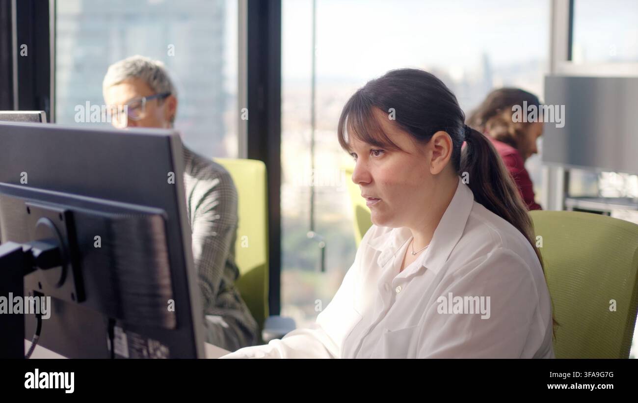 Konzentrierte Geschäftsfrau arbeitet am Computer in einem modernen Großraumbüro Stockfoto